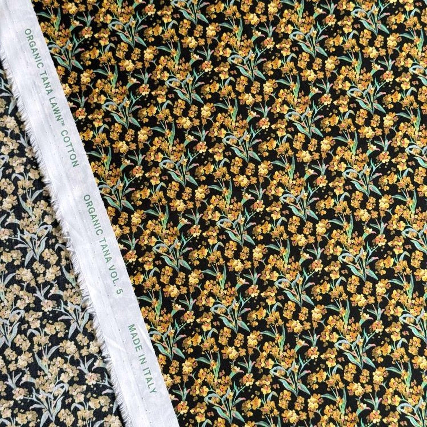 a close-up view of a fabric with a floral pattern, including yellow flowers and green leaves. The fabric appears to be made of organic cotton and is displayed alongside a white label that reads "Organic TANA LYNCH COTTON VOL. 5 MADE IN ITALY".