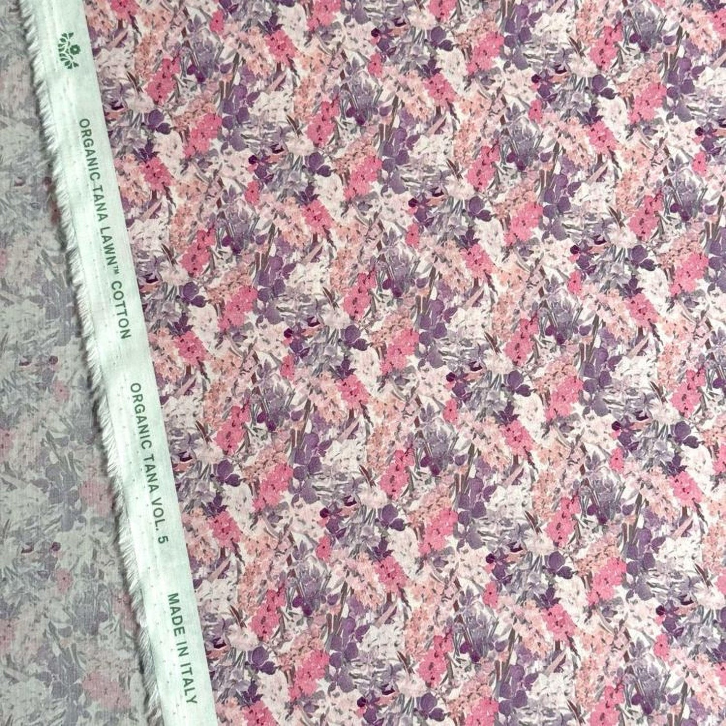 a fabric with a floral pattern in shades of pink and purple. The fabric appears to be made of organic cotton and is labeled as "Organic Lawn Cotton" and "Made in Italy".