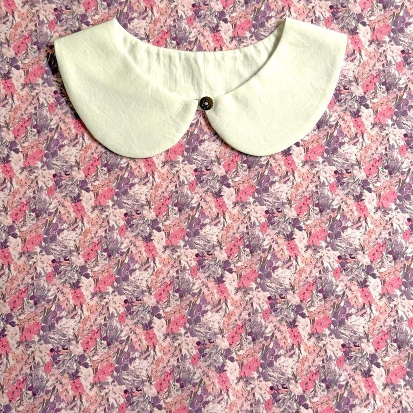 A white collar is displayed on a floral print fabric.