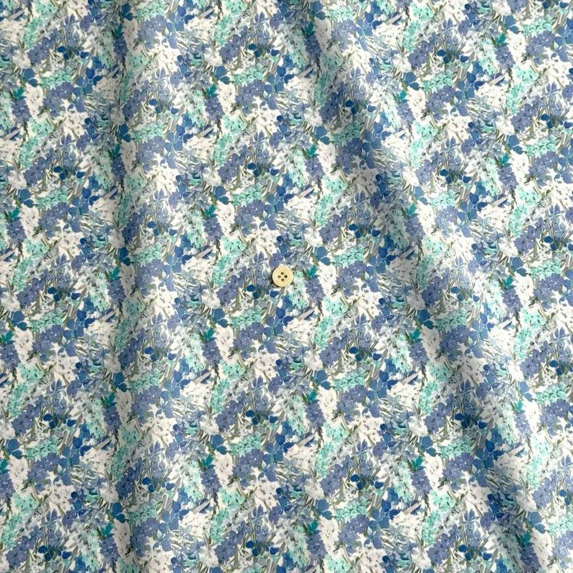 a close-up view of a fabric with a floral pattern in shades of blue and white. The fabric appears to be made of a soft, textured material, and there is a small button visible in the center of the fabric.