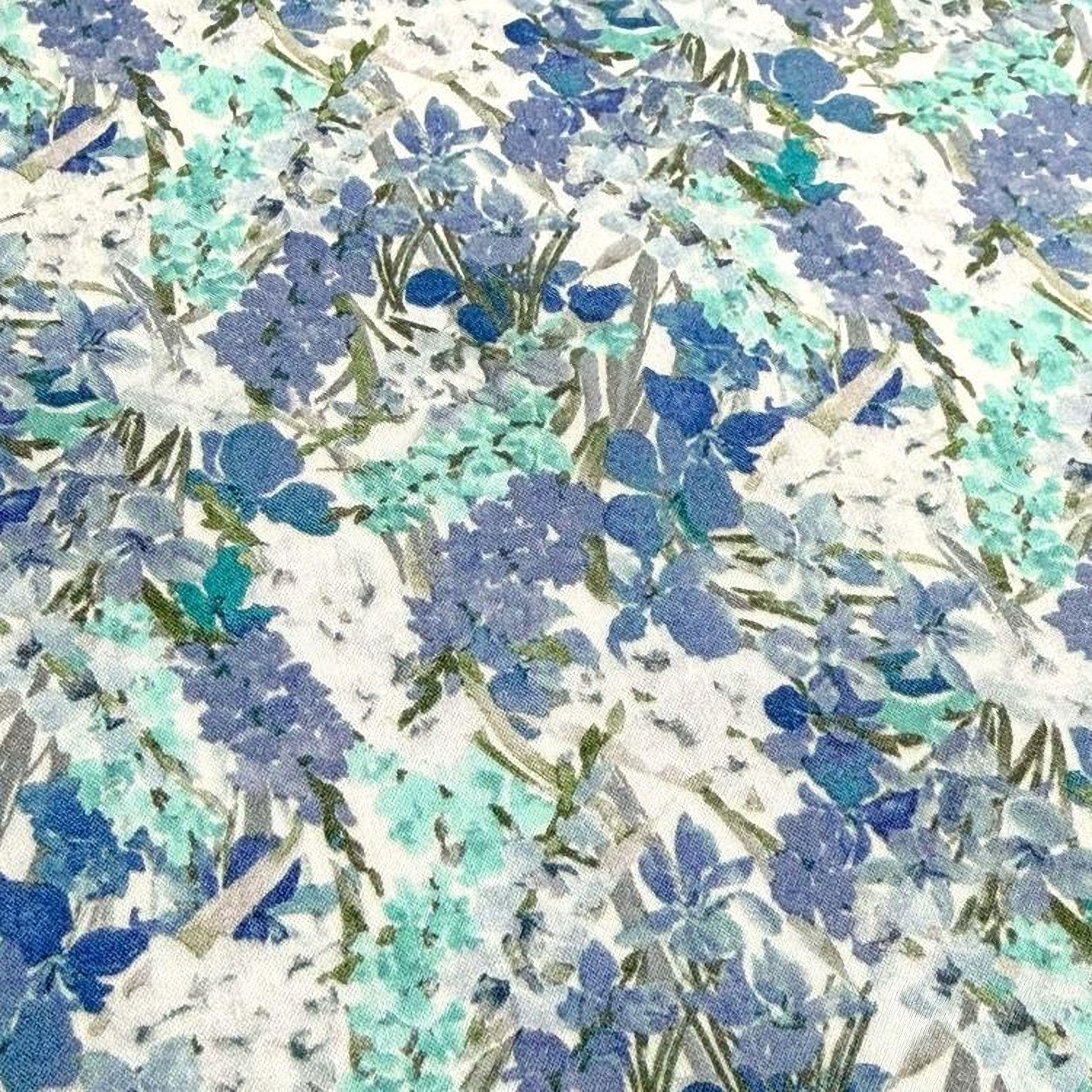 The image is a close-up of a fabric with a floral pattern in shades of blue and green. The pattern consists of various flowers and leaves, creating a visually appealing and intricate design.