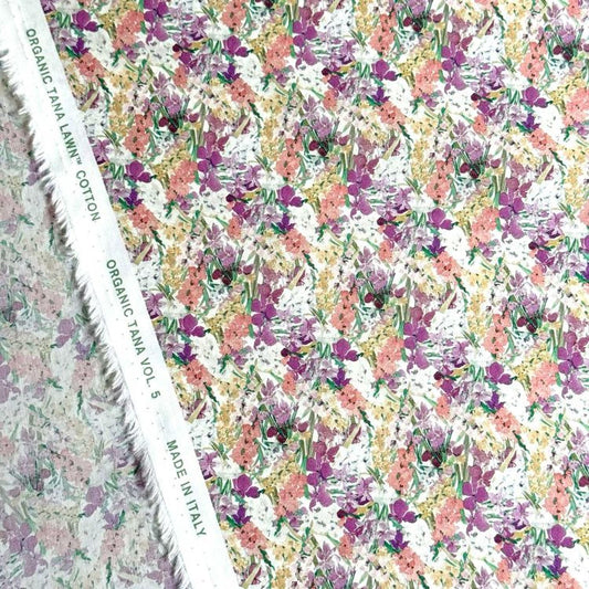a fabric with a floral pattern, including various shades of pink, yellow, and green flowers. The fabric appears to be made of organic cotton and is displayed on a white background.