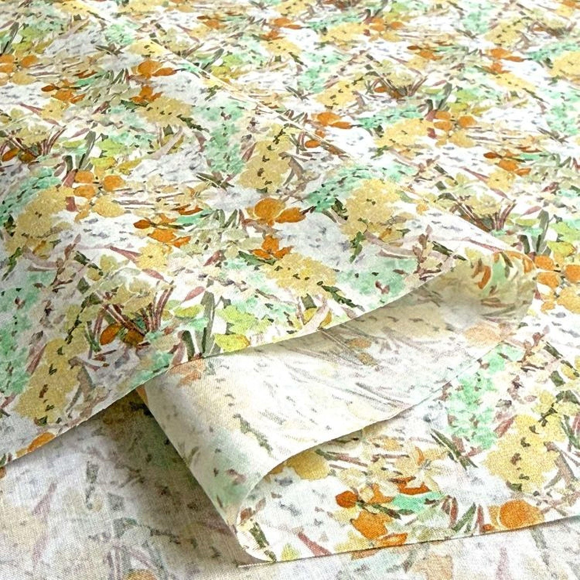 a close-up view of a fabric with a floral pattern in shades of yellow, green, and orange. The fabric appears to be a piece of paper or a textile with a printed design.