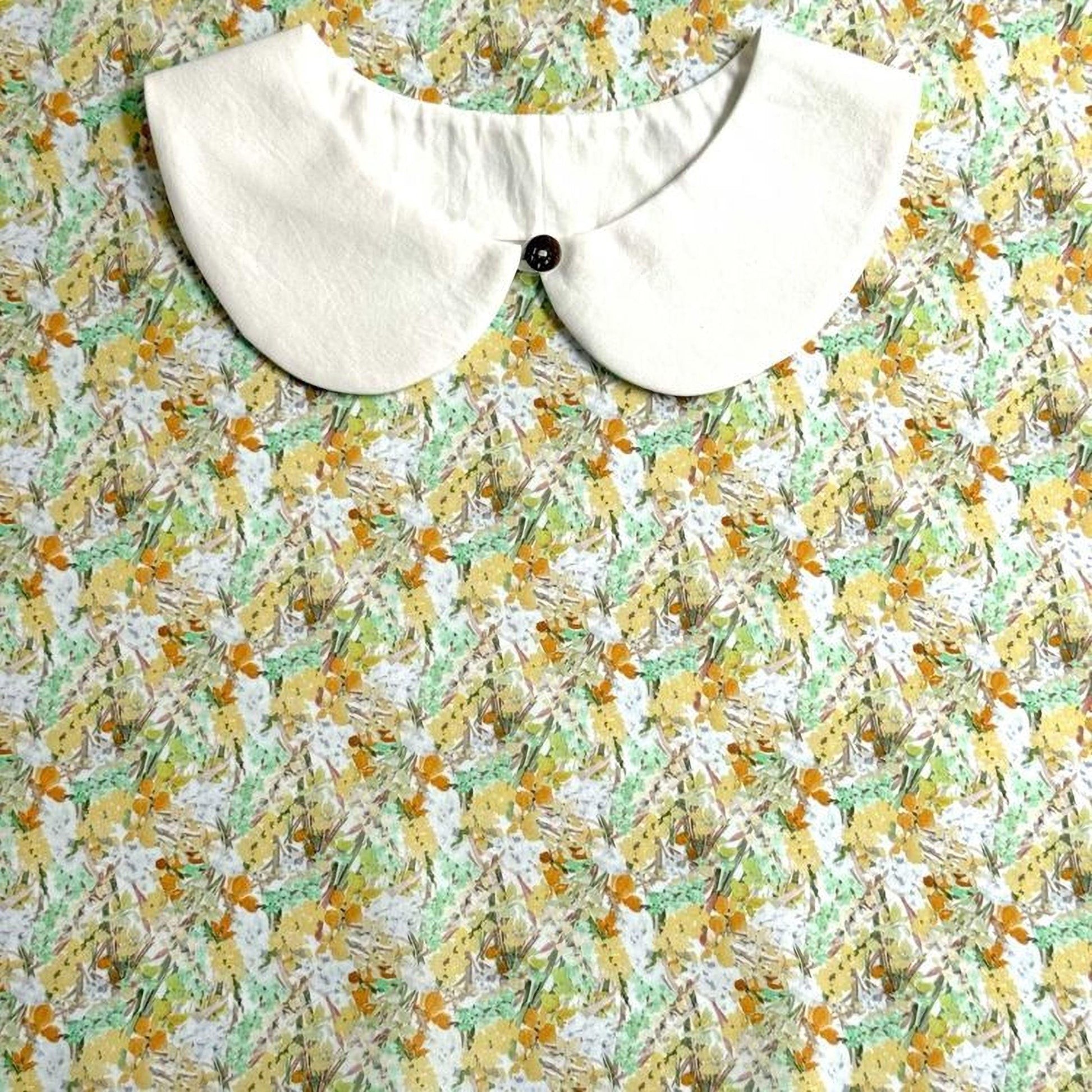 a white collar with a button, set against a background with a floral print.
