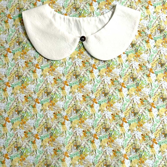 a white collar with a button, set against a background with a floral print.
