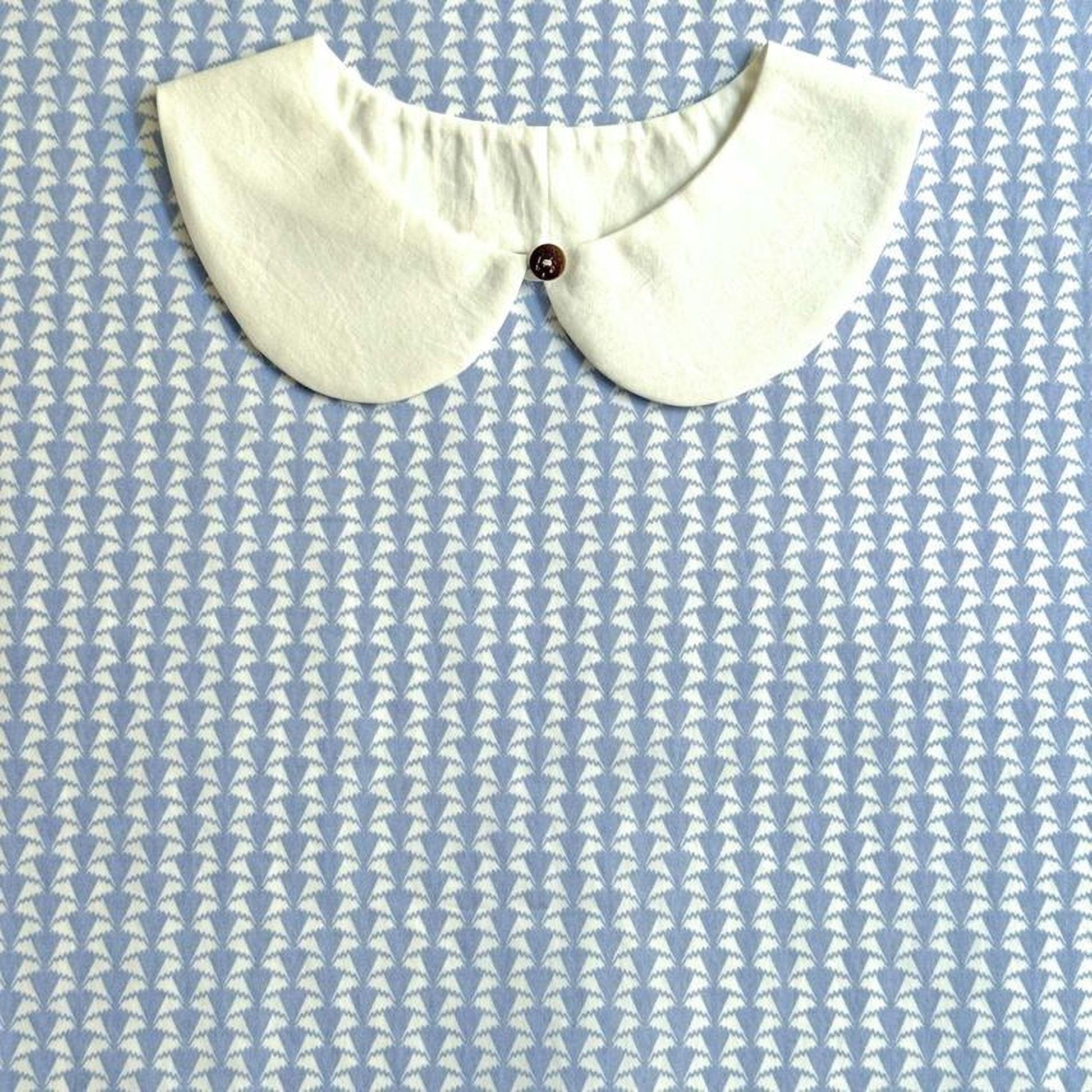 A white collar is displayed against a blue and white patterned background.