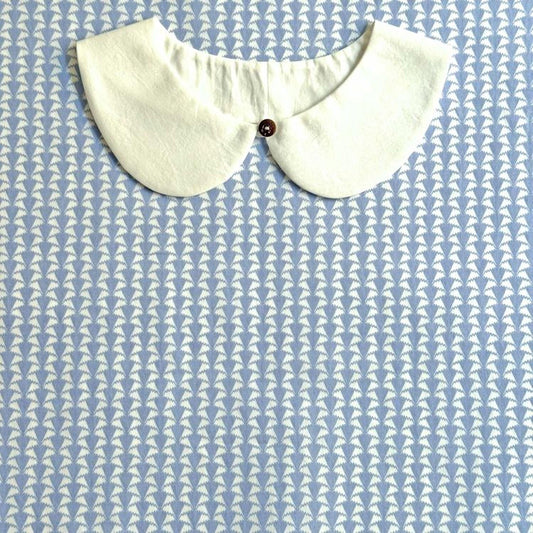 A white collar is displayed against a blue and white patterned background.