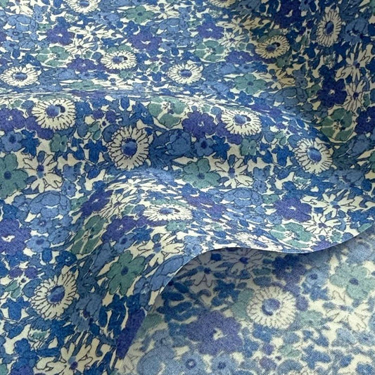 a close-up view of a fabric with a blue and white floral pattern. The fabric appears to be folded or crumpled, creating a textured and visually interesting surface.