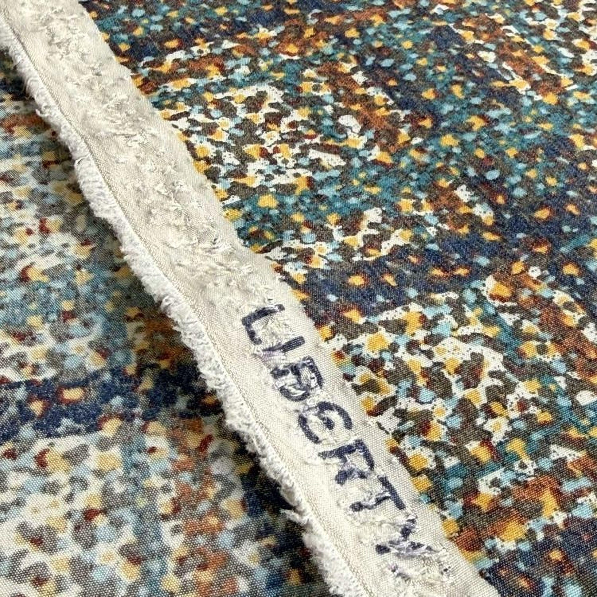 a close-up view of a colorful, abstract patterned fabric with a frayed edge.