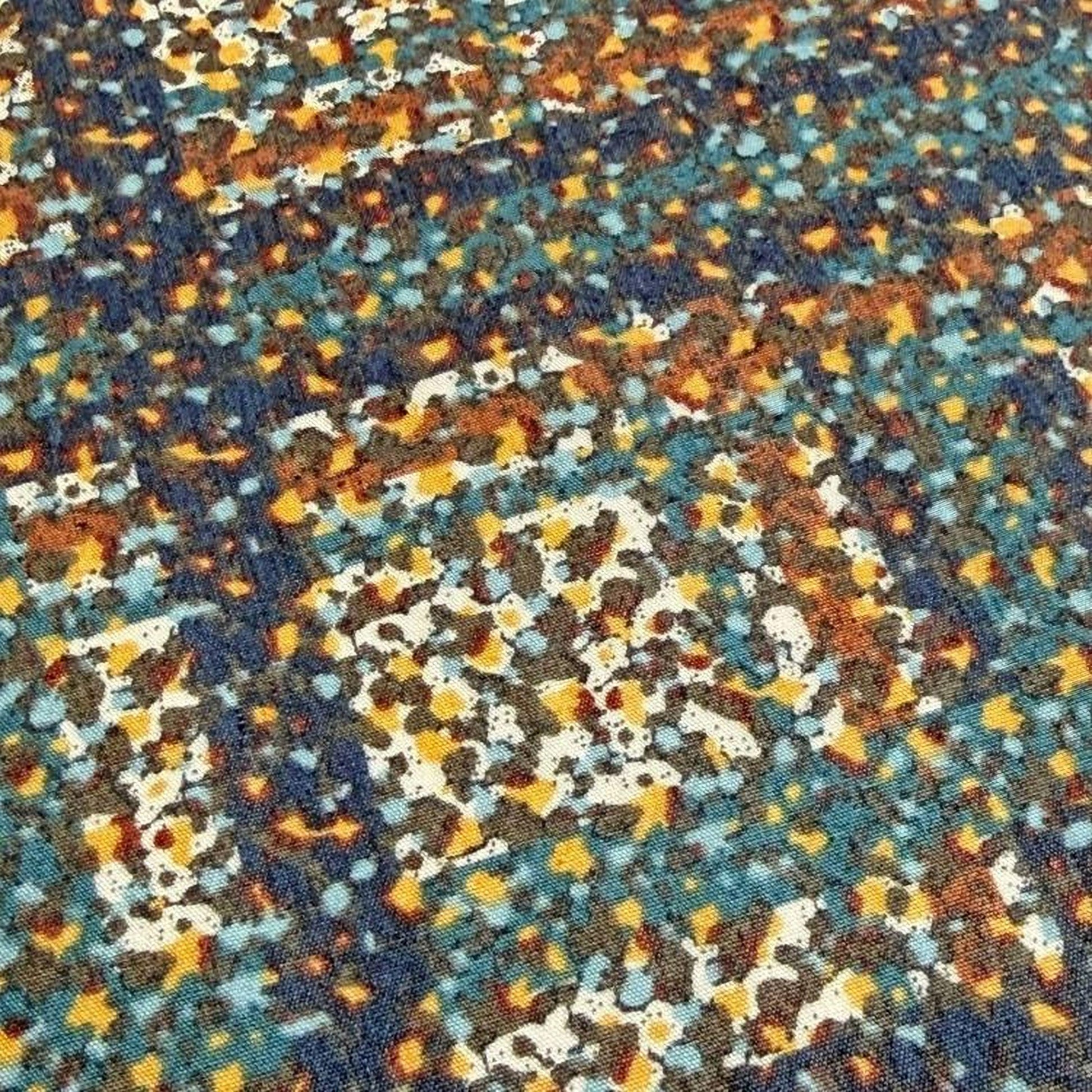 The image is a close-up of a fabric with a colorful, abstract pattern of small dots in various shades of blue, orange, and yellow.