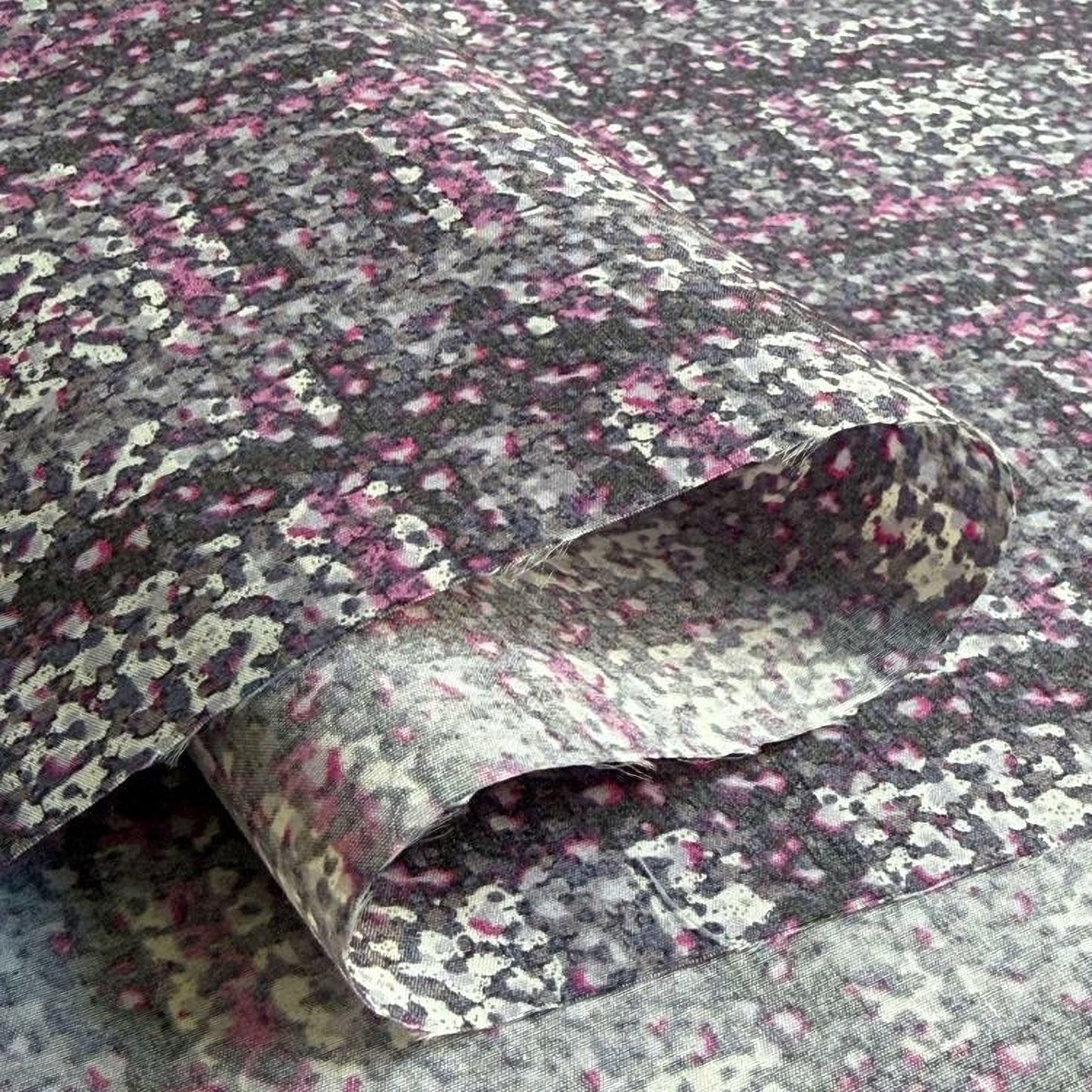 a close-up view of a fabric with a floral pattern in shades of pink, gray, and black.
