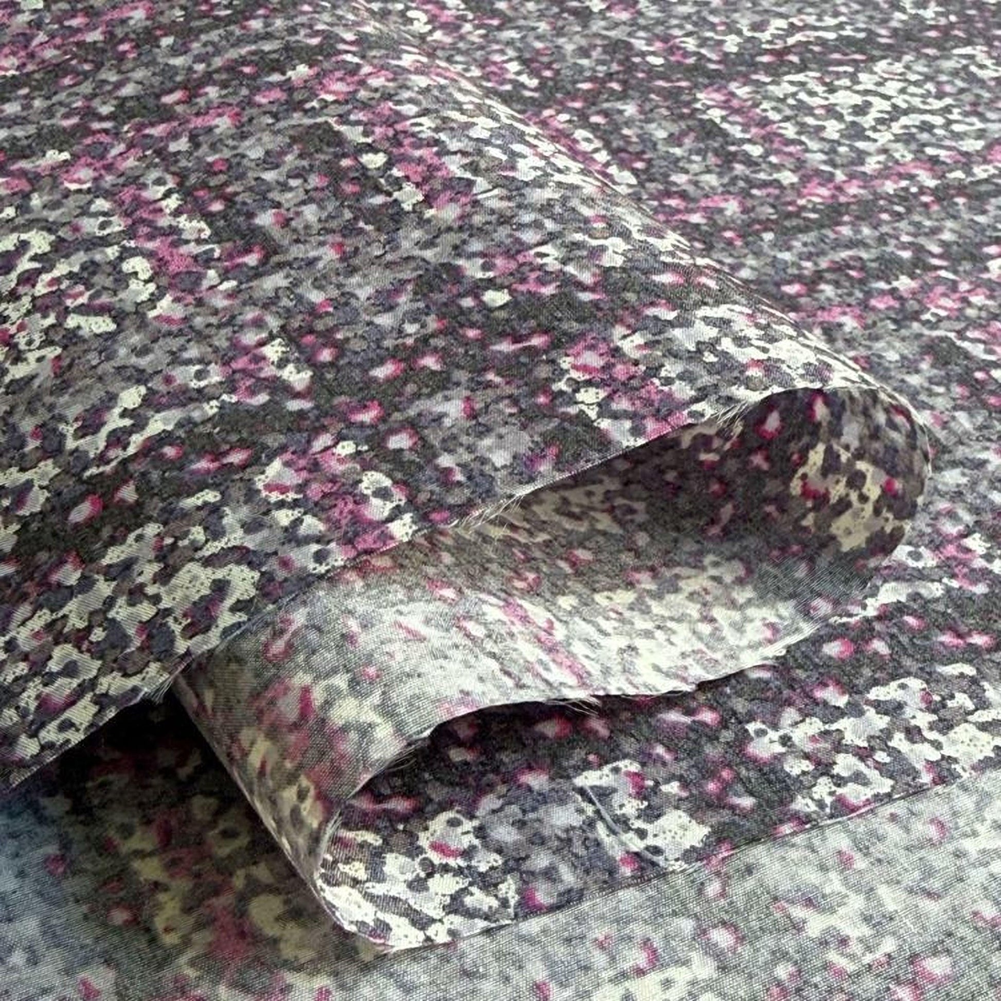 a close-up view of a fabric with a floral pattern in shades of pink, gray, and black.