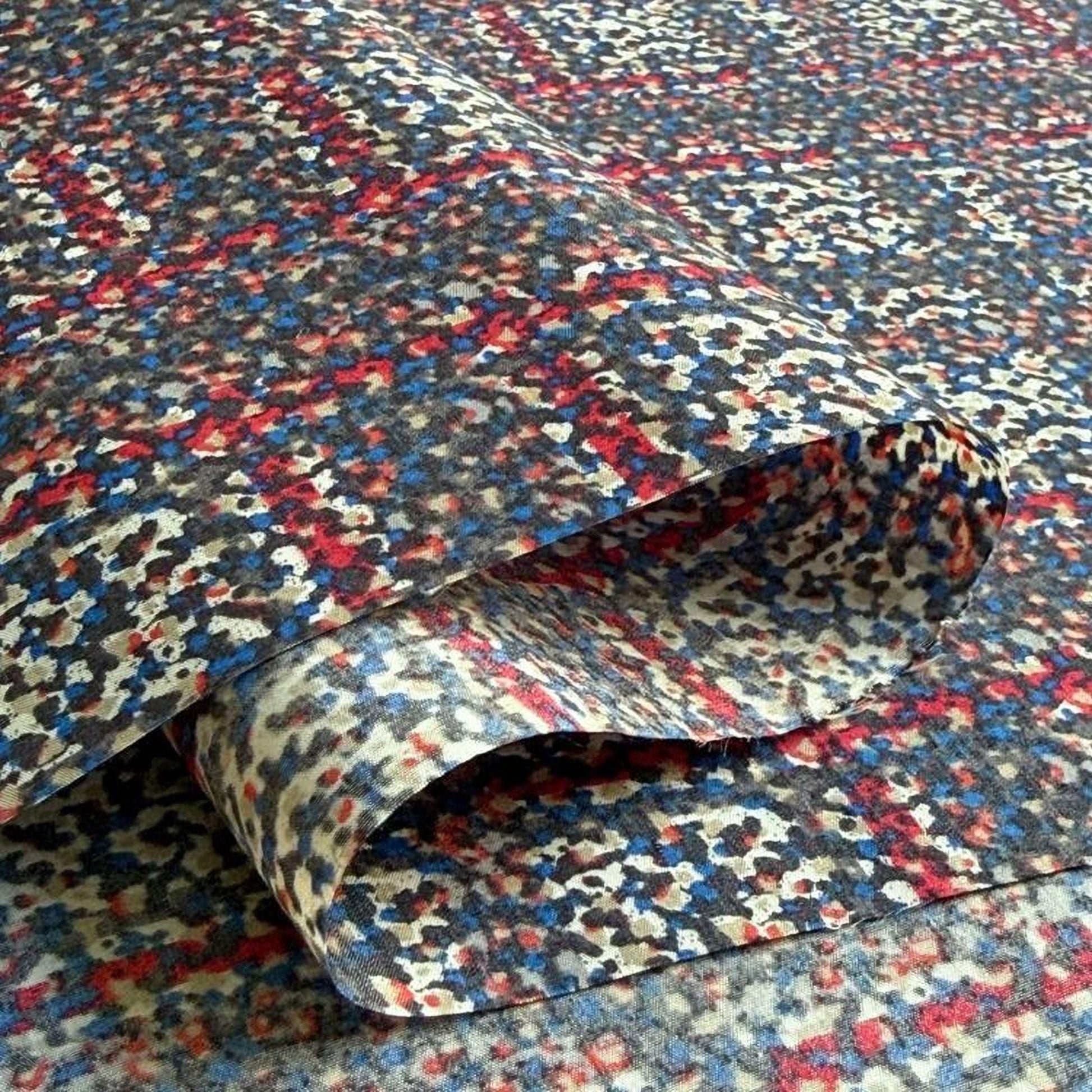 a close-up view of a fabric with a vibrant, multicolored pattern. The fabric appears to be folded or rolled, revealing its intricate design.