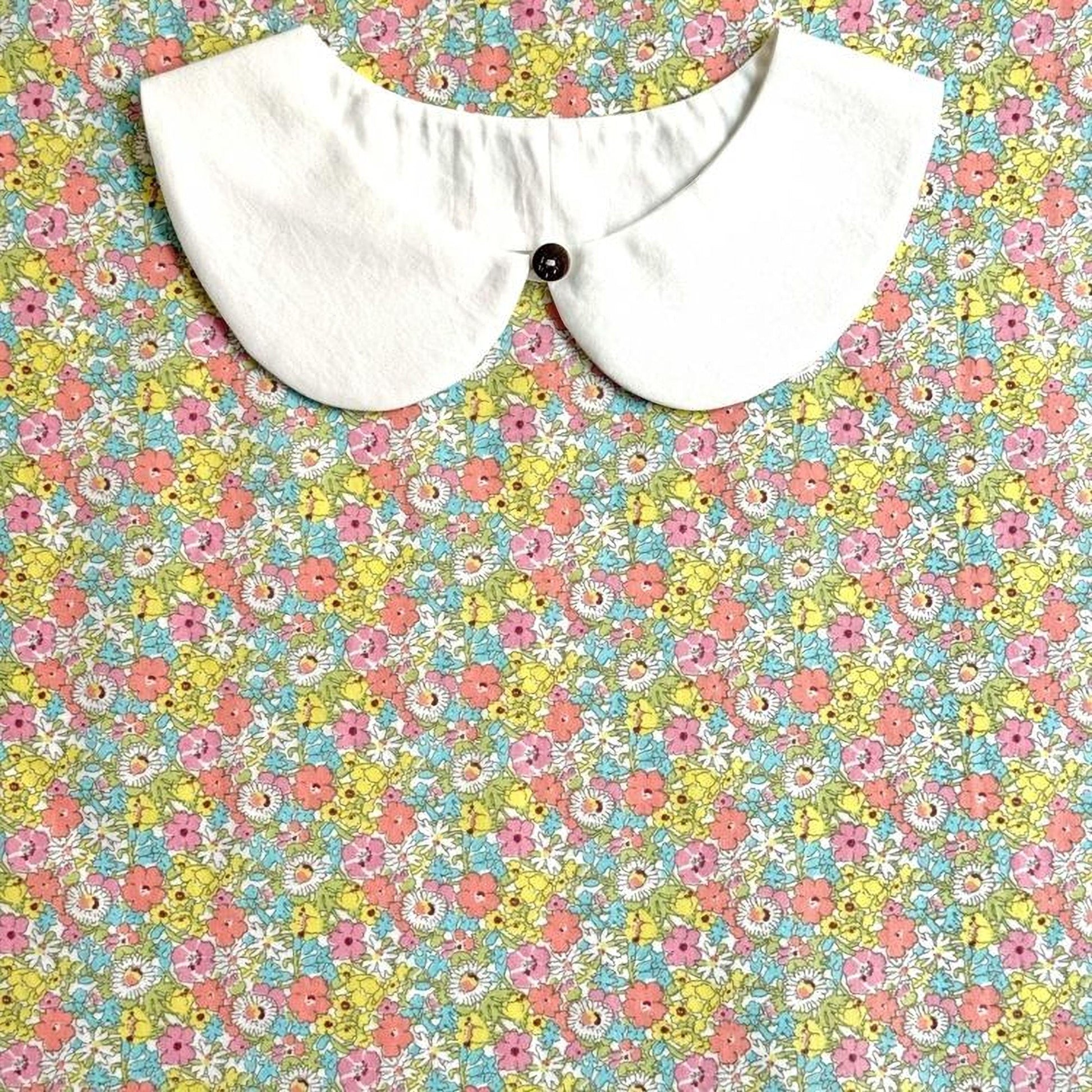 A white collar is displayed against a colorful floral background.