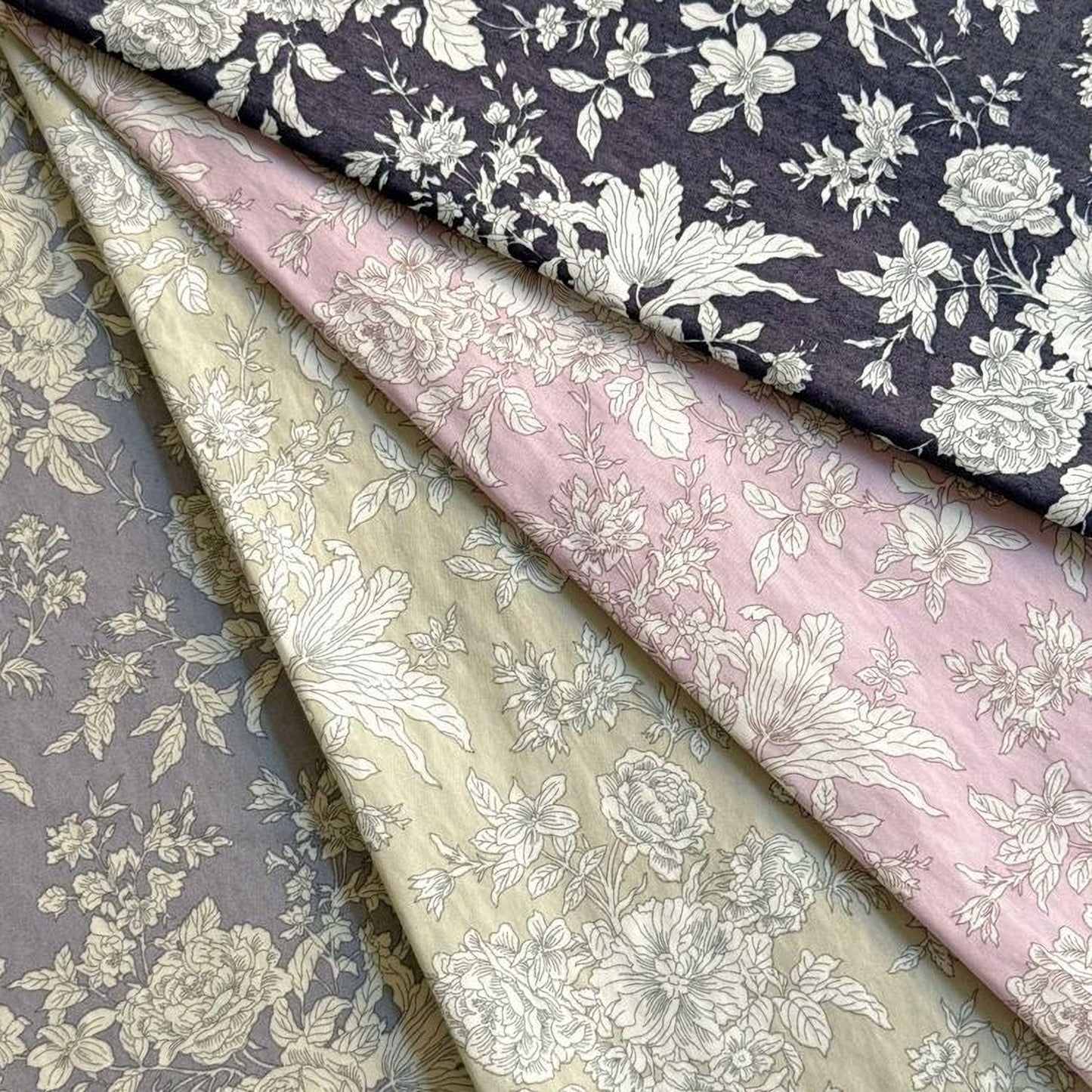 four fabric swatches with floral patterns in various shades of gray, pink, and blue.