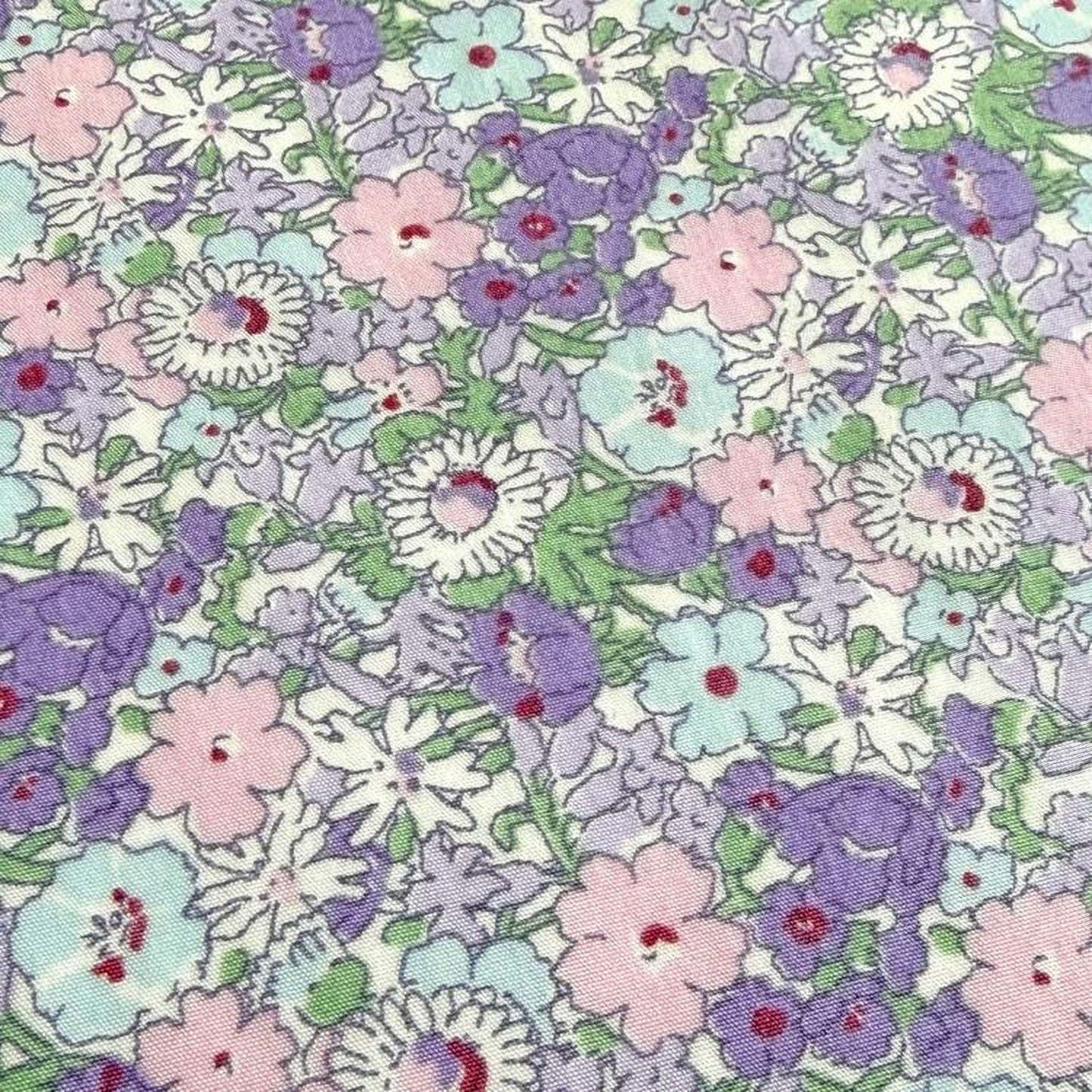 The image is a close-up of a fabric with a floral pattern, featuring a variety of colorful flowers in shades of pink, purple, and white.