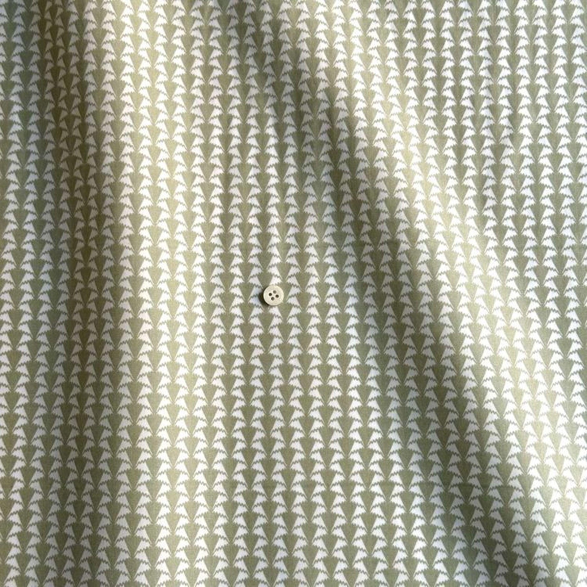 a close-up view of a fabric with a repeating pattern of white triangles. The pattern is arranged in a diagonal line across the fabric, creating a sense of movement and rhythm. The fabric appears to be a light green color, which complements the white triangles and adds a touch of color to the overall composition. The image does not contain any text or other discernible objects, and the relative positions of the objects are consistent with the diagonal pattern of the fabric.
