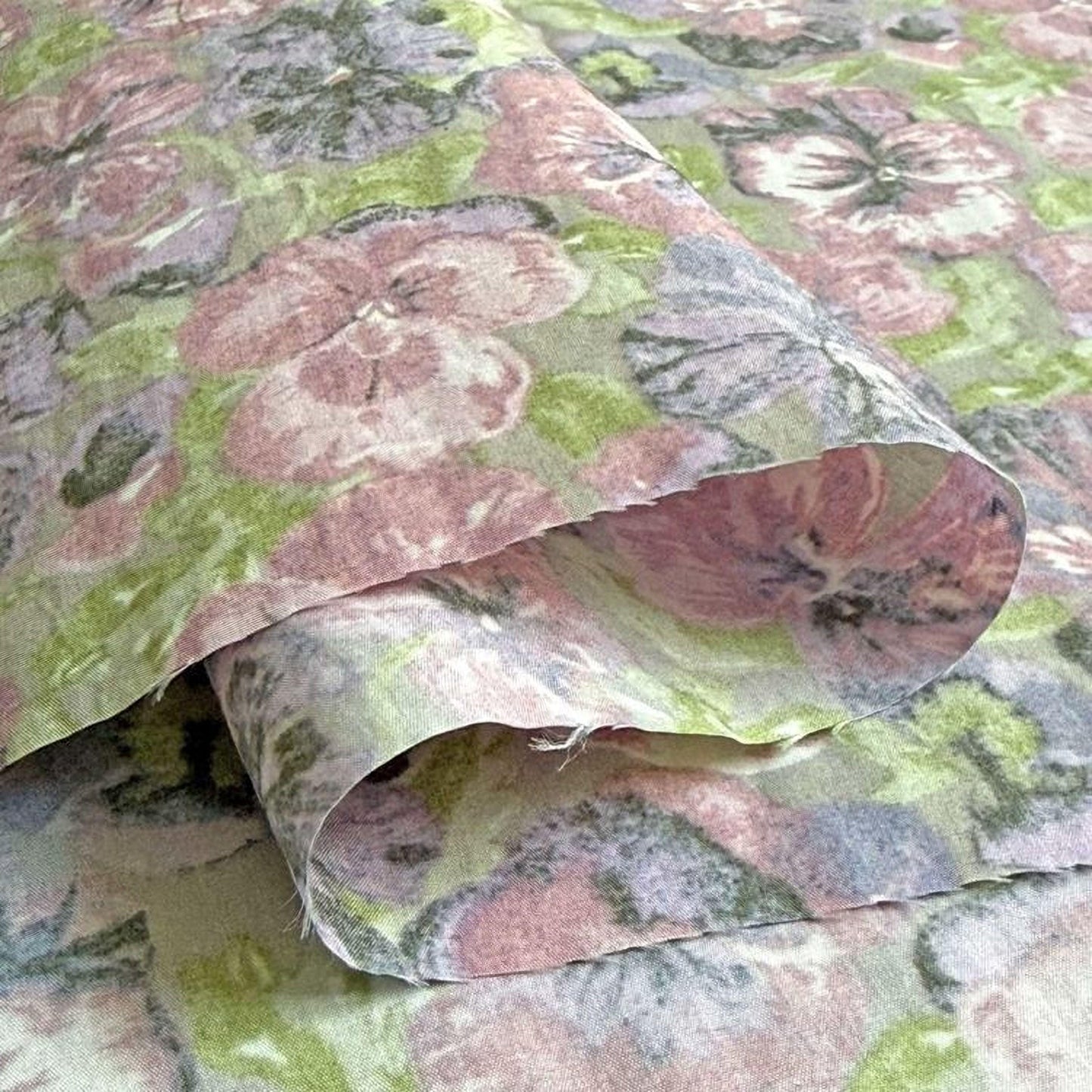 a close-up view of a fabric with a floral pattern, featuring a mix of pink, green, and purple colors.