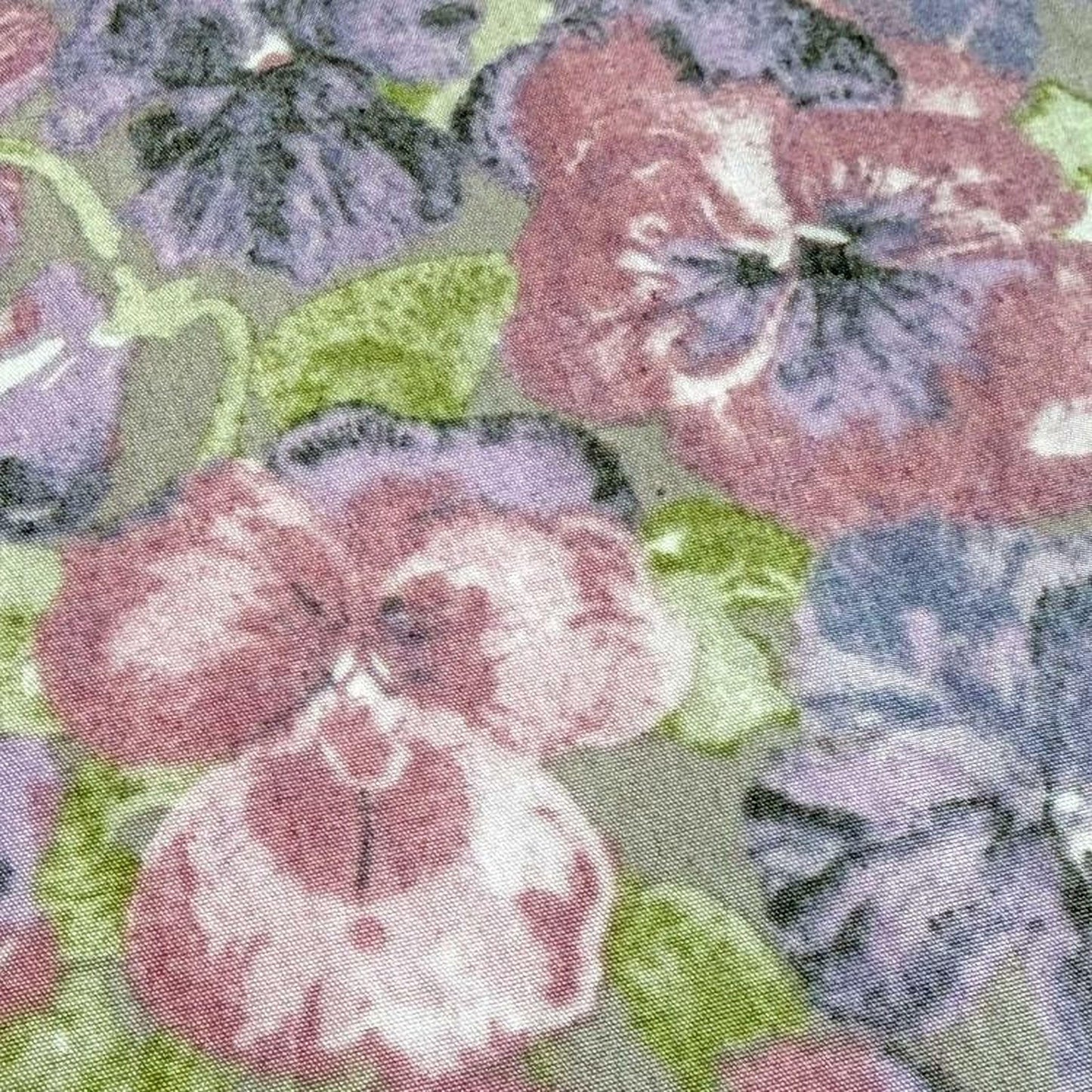 a close-up view of a fabric with a floral pattern, including various shades of purple and pink flowers.