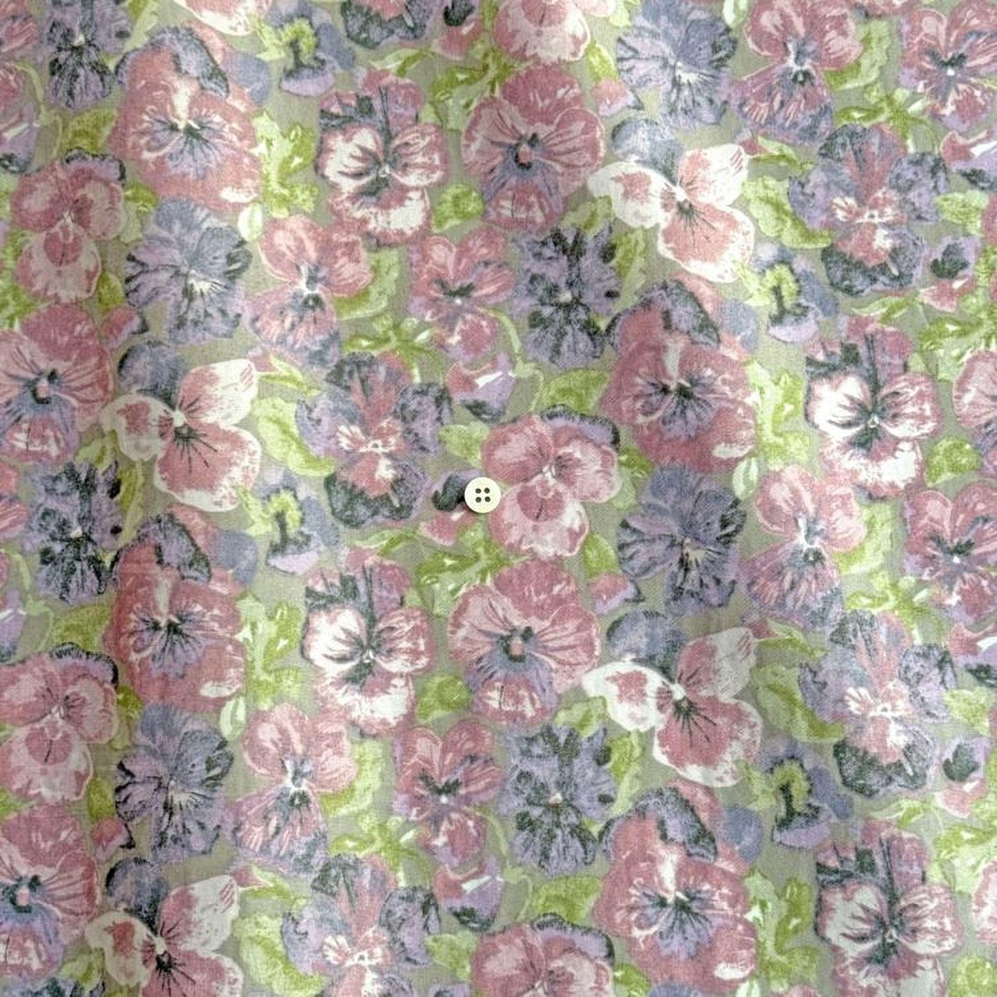 a close-up view of a fabric with a floral pattern, including pink, purple, and green flowers. There is a small white button visible in the center of the fabric.
