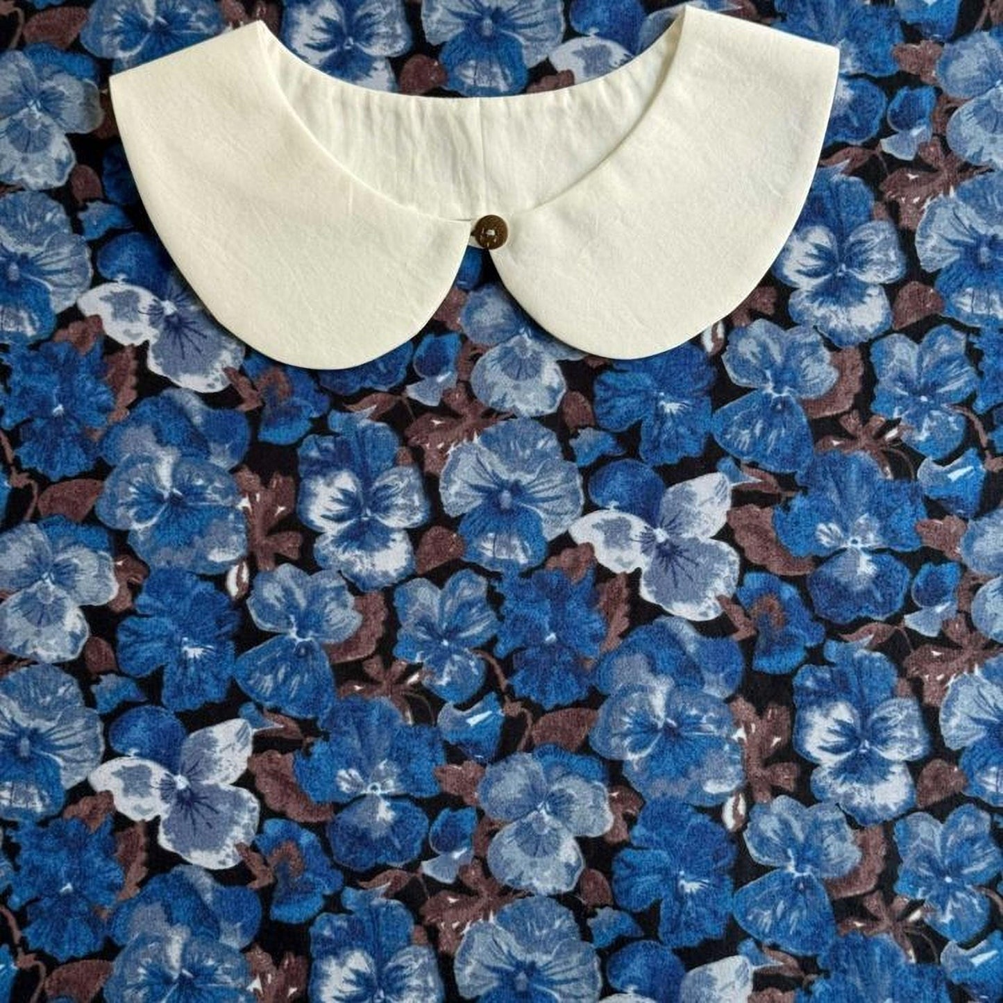 a white collar against a background of blue and brown floral patterns.