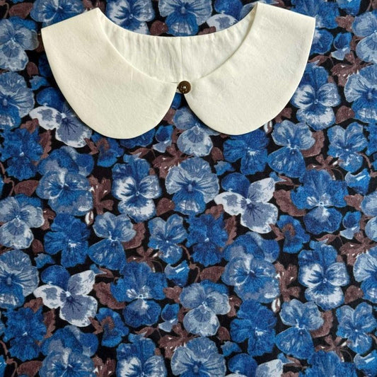a white collar against a background of blue and brown floral patterns.