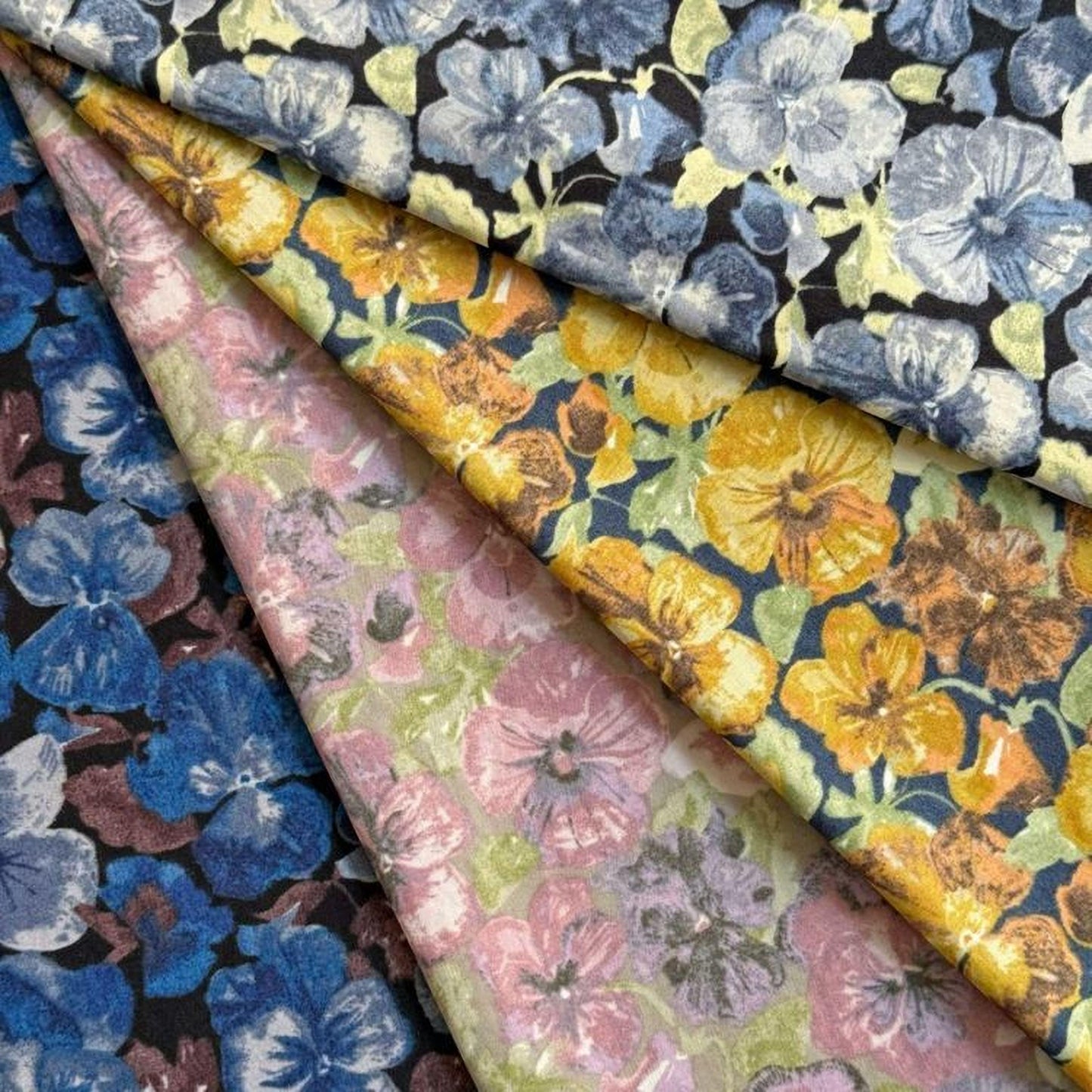 a collection of fabric swatches with various floral patterns, including blue, yellow, and pink flowers.
