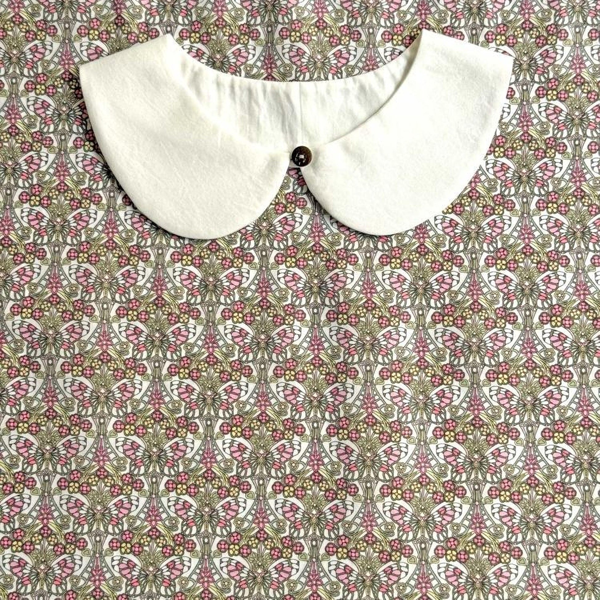 a white collar with a button, set against a patterned fabric with a floral design.