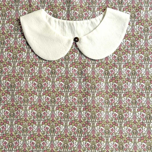a white collar with a button, set against a patterned fabric with a floral design.
