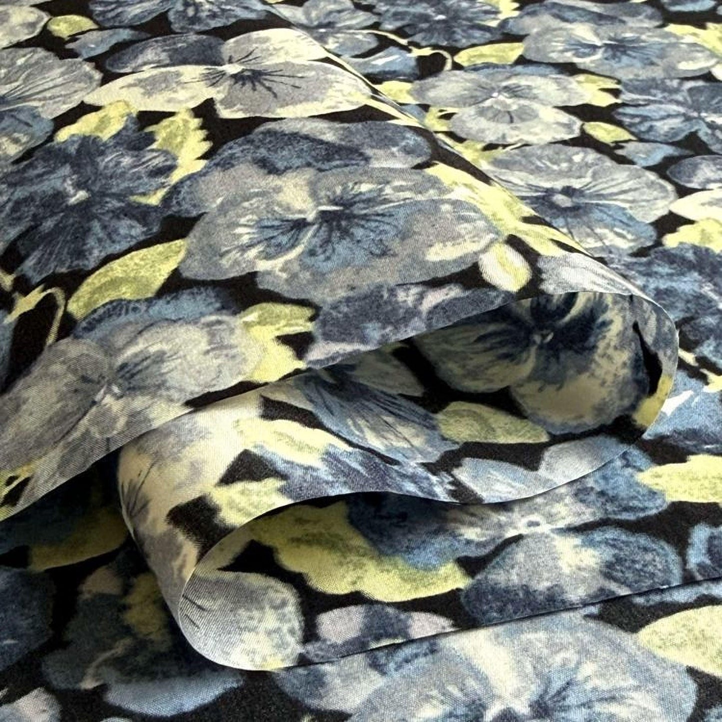 a close-up view of a fabric with a floral pattern, featuring various shades of blue, green, and yellow flowers.