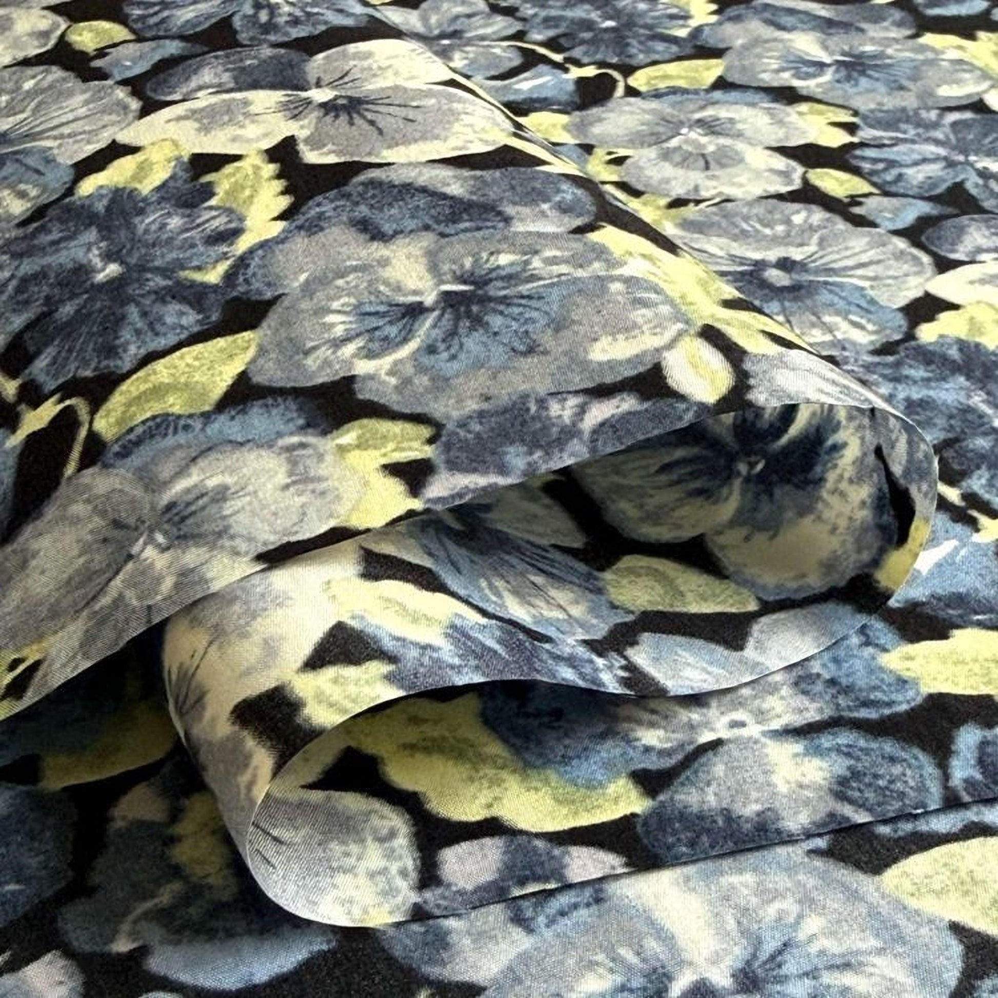 a close-up view of a fabric with a floral pattern, featuring various shades of blue, green, and yellow flowers.
