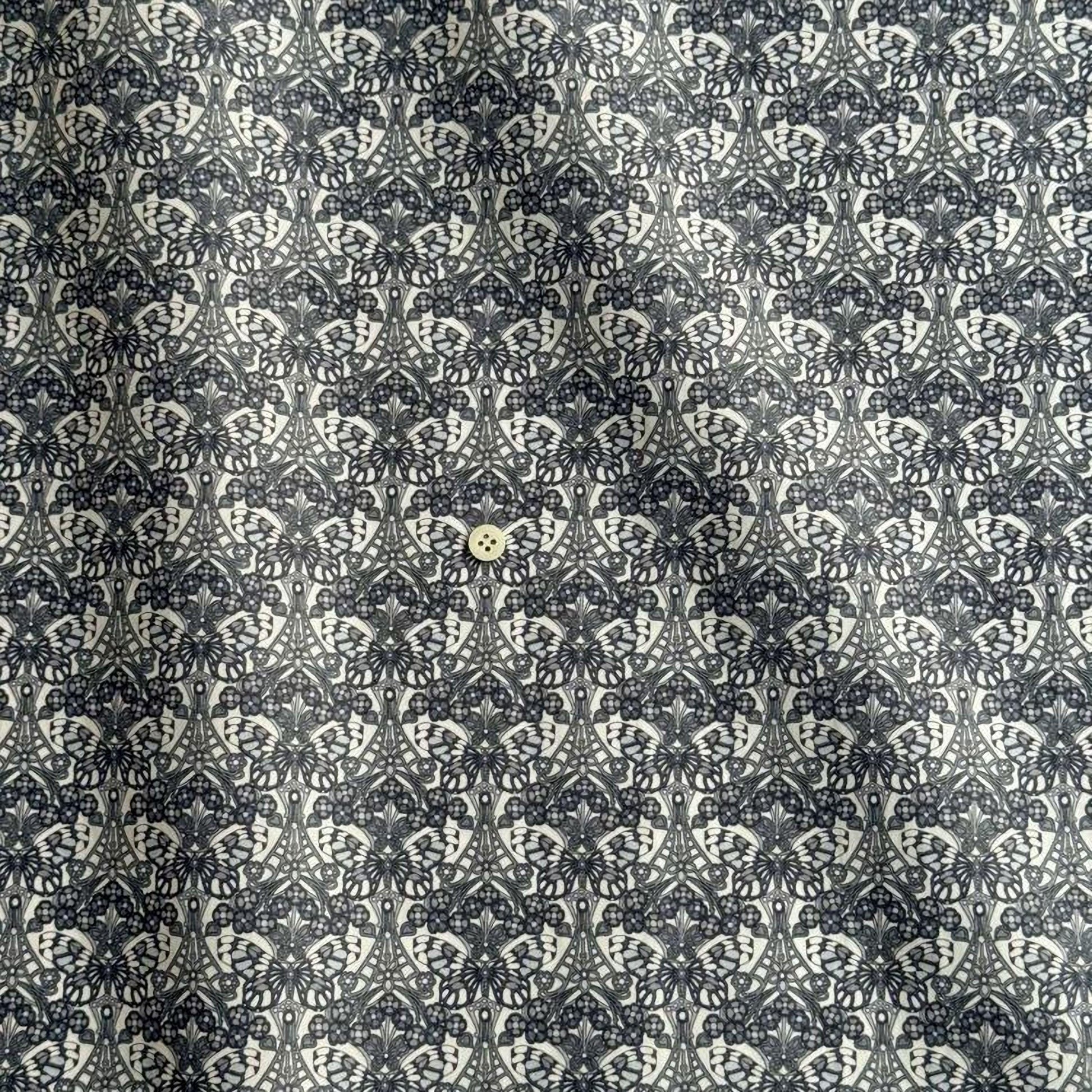a repeating pattern of black and white floral designs, with a small white button placed in the center of the pattern.