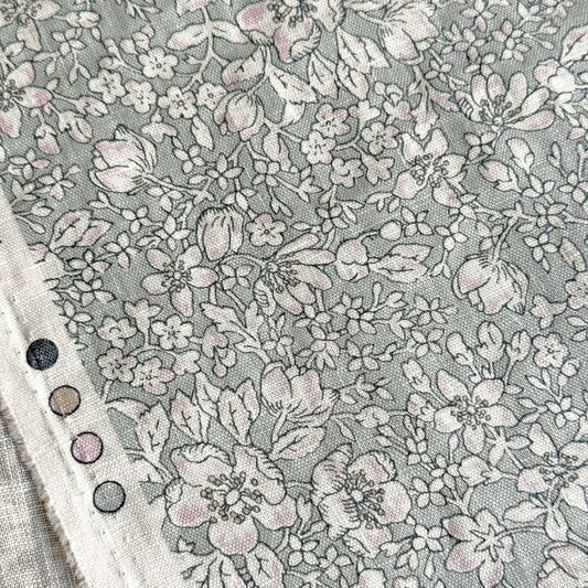 a close-up view of a fabric with a floral pattern, featuring various shades of gray and white flowers and leaves.