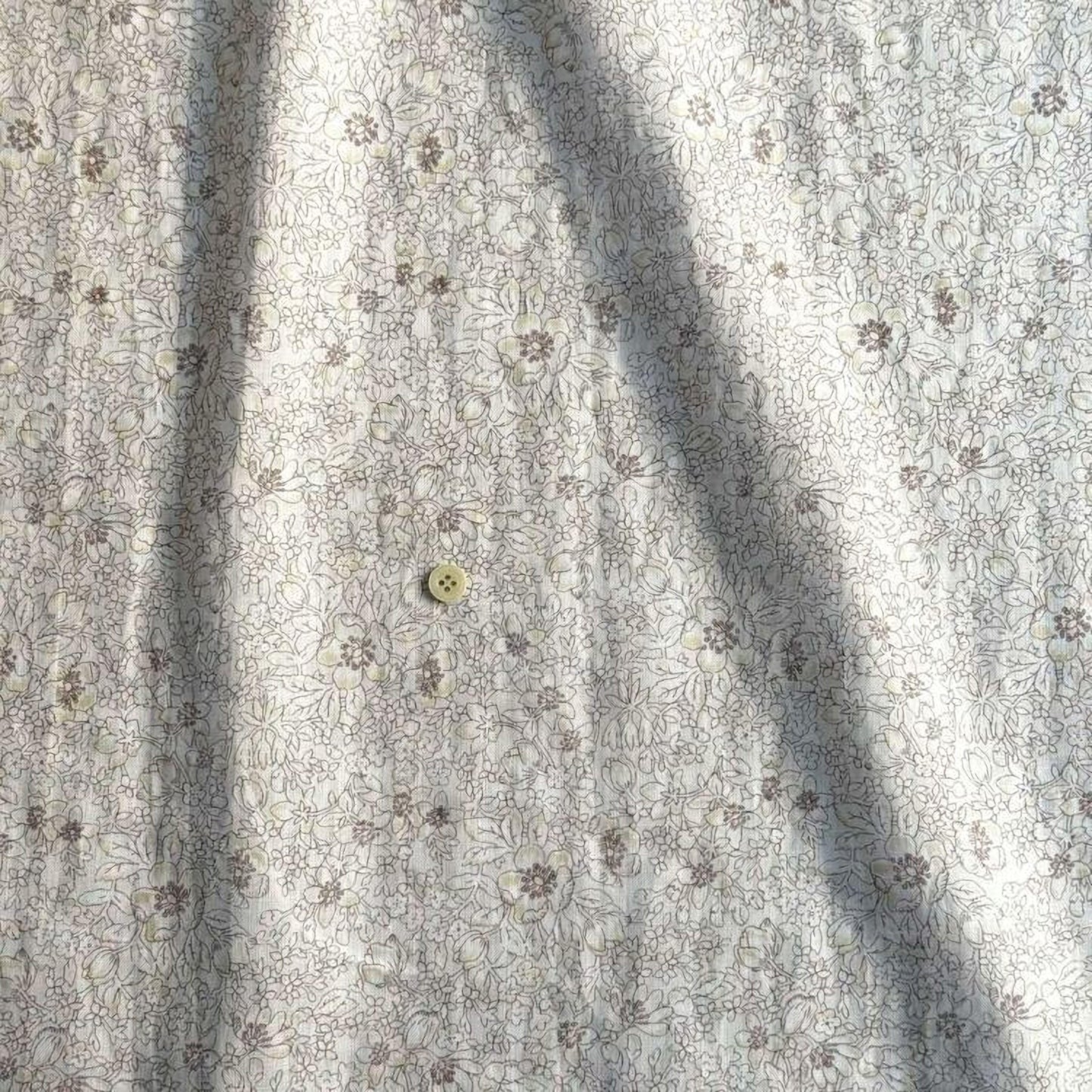 a close-up view of a fabric with a floral pattern, featuring a small button in the center.