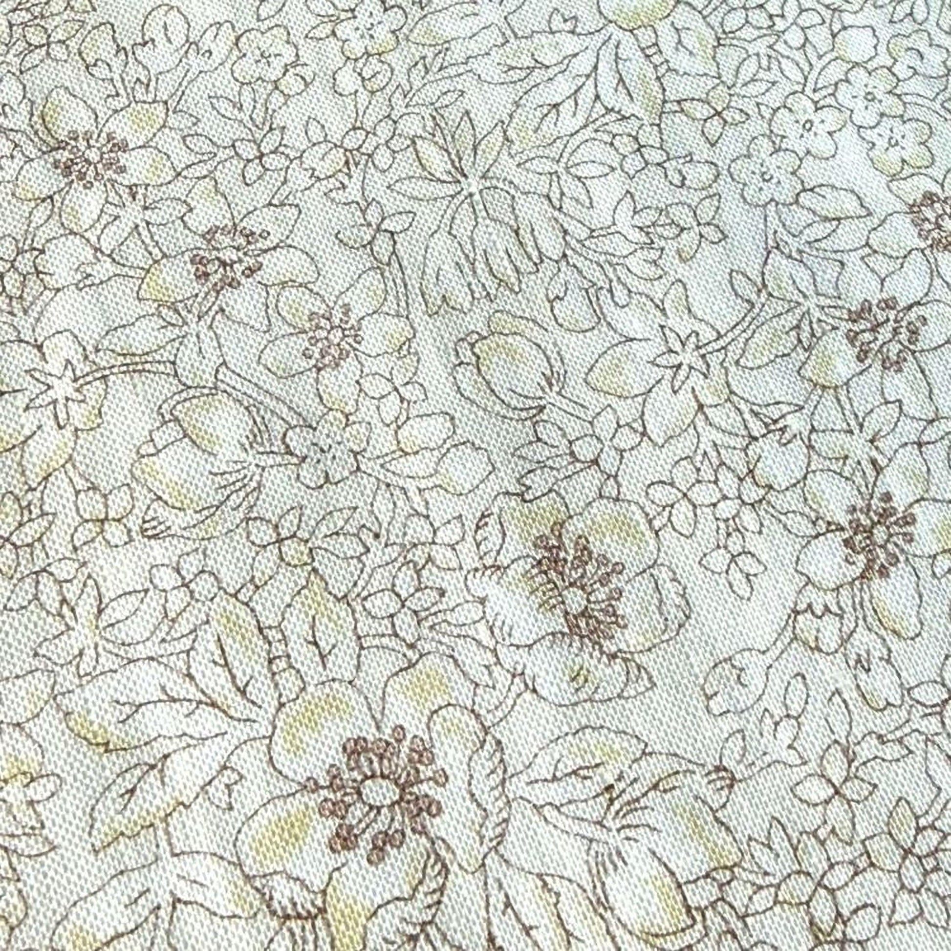 The image is a close-up of a fabric with a floral pattern, featuring various types of flowers and leaves in different shades of brown and beige.