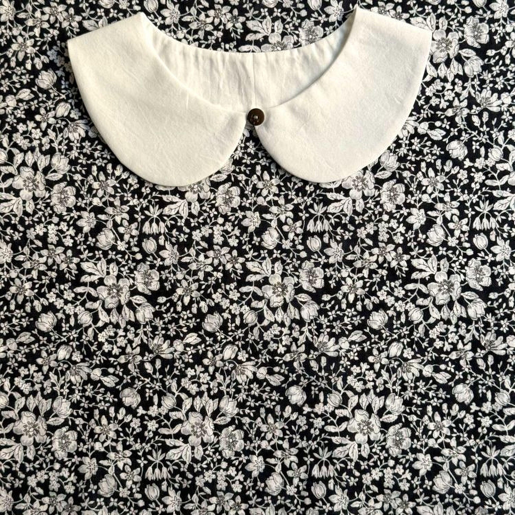 a close-up view of a white collar on a black and white floral print dress.
