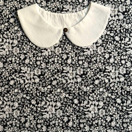 a close-up view of a white collar on a black and white floral print dress.