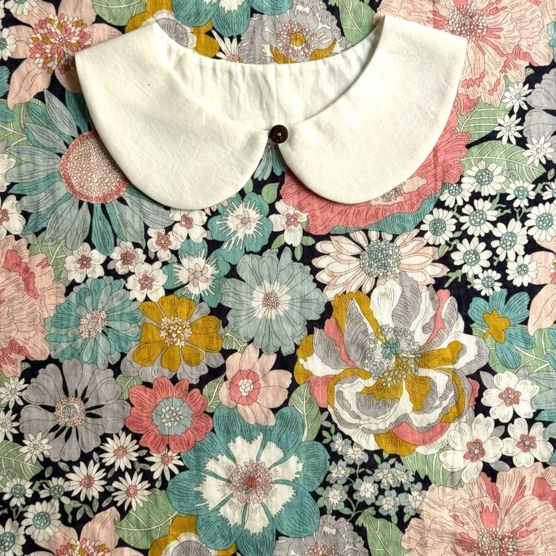 a white collar with a button, set against a background of a colorful floral print.