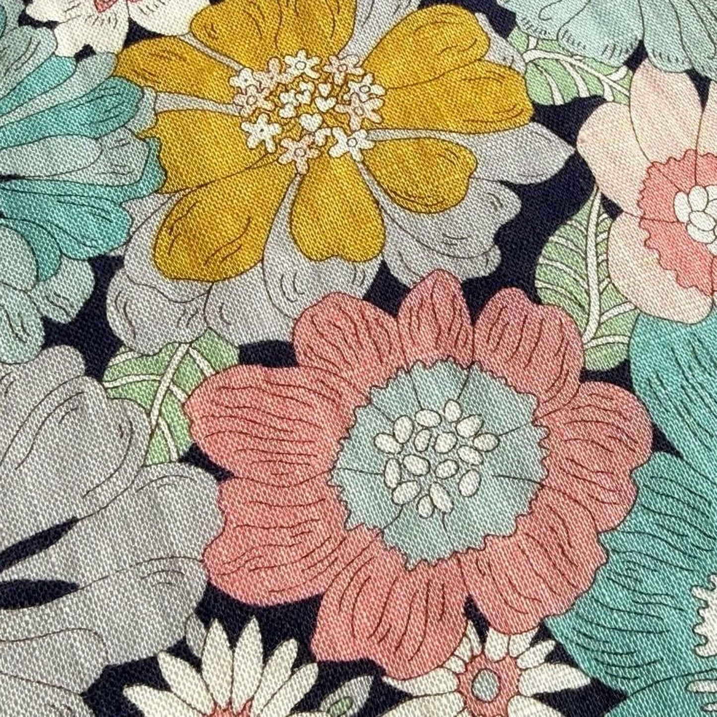 a close-up view of a fabric with a vibrant floral pattern. The fabric is adorned with a variety of colorful flowers, including yellow, pink, and blue flowers, as well as green leaves. The flowers are intricately detailed, showcasing the craftsmanship and artistry of the fabric design.