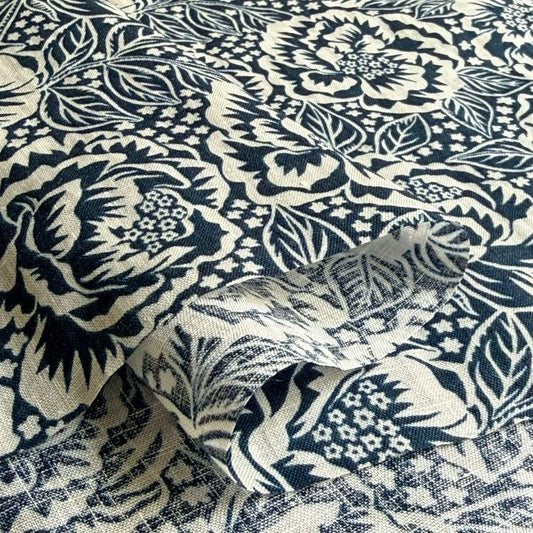 a close-up view of a fabric with a floral pattern in shades of blue and white. The pattern consists of various flowers and leaves, creating a visually striking and intricate design. The fabric appears to be a piece of cloth or textile, with the intricate floral pattern suggesting it could be used for clothing or home decor.