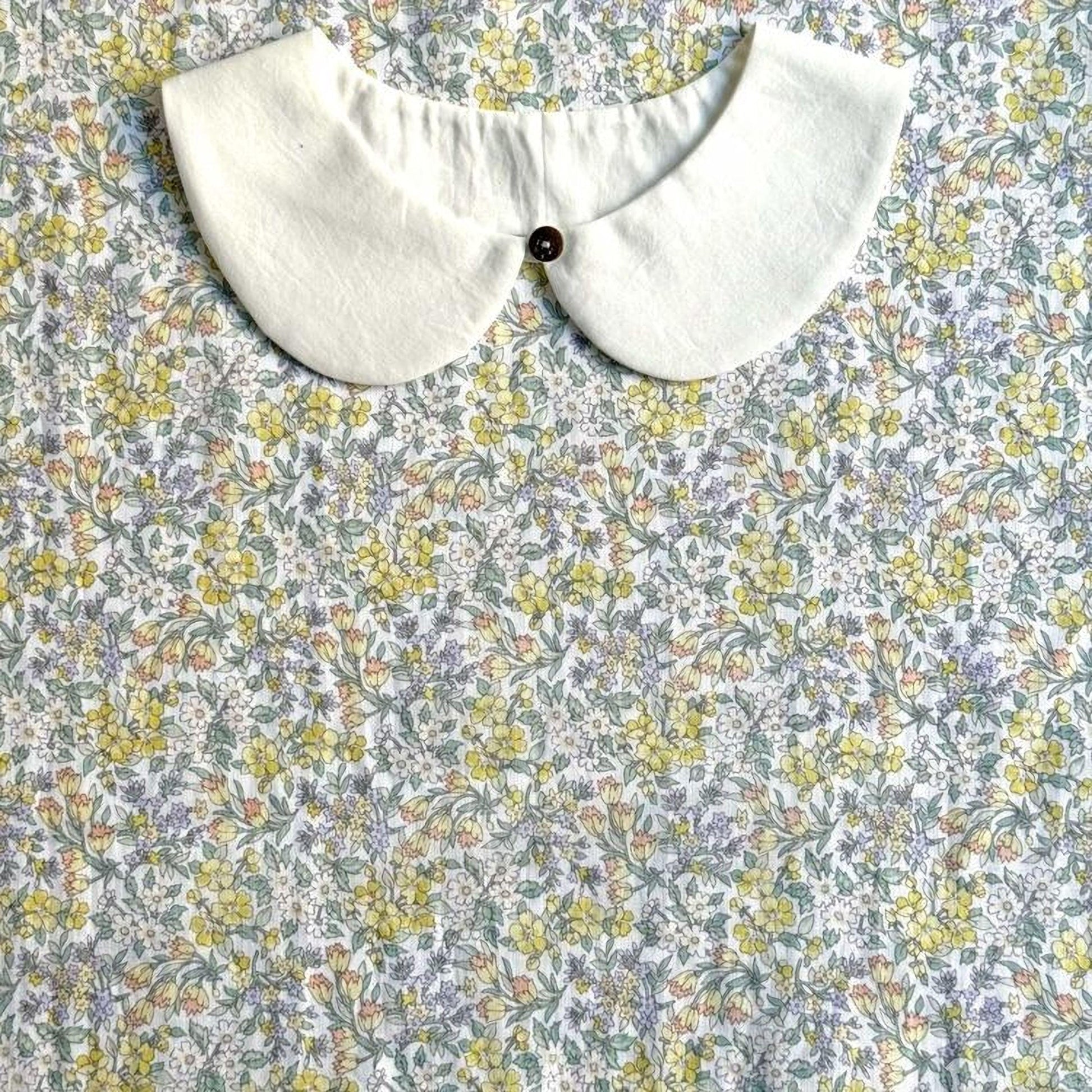 a white collar with a button, set against a background of a floral print fabric.