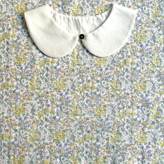 a white collar with a button, set against a background of a floral print fabric.