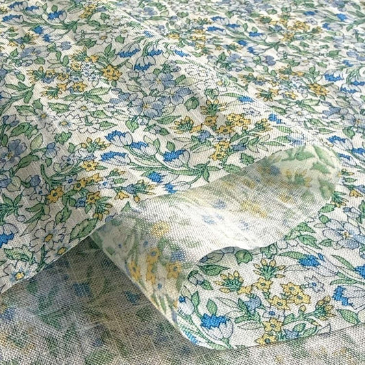 a close-up view of a fabric with a floral pattern in shades of green, blue, and yellow. The fabric appears to be a piece of cloth or textile, with the pattern and colors creating a visually appealing design.