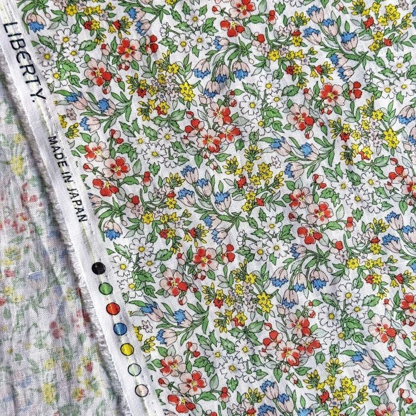 a close-up view of a fabric with a vibrant floral pattern, including various colors and shapes of flowers and leaves.