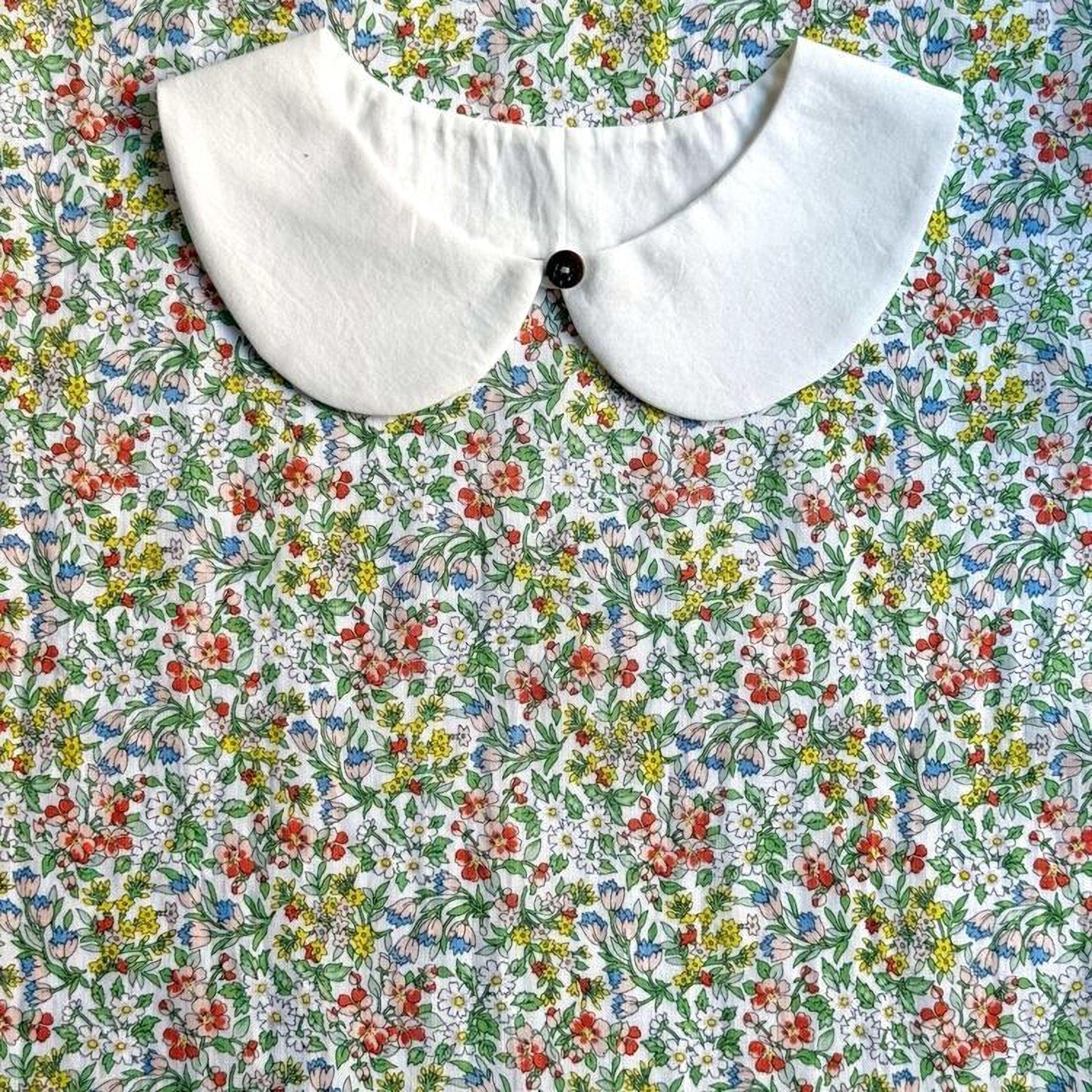 a white collar with a button, set against a background of a colorful floral print.