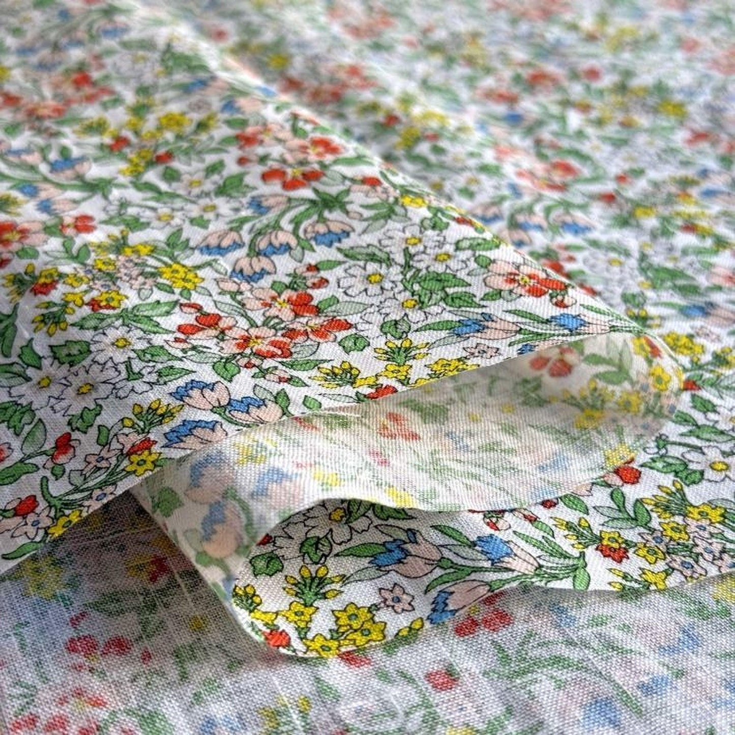 a close-up view of a fabric with a floral pattern, featuring a variety of colorful flowers and leaves.