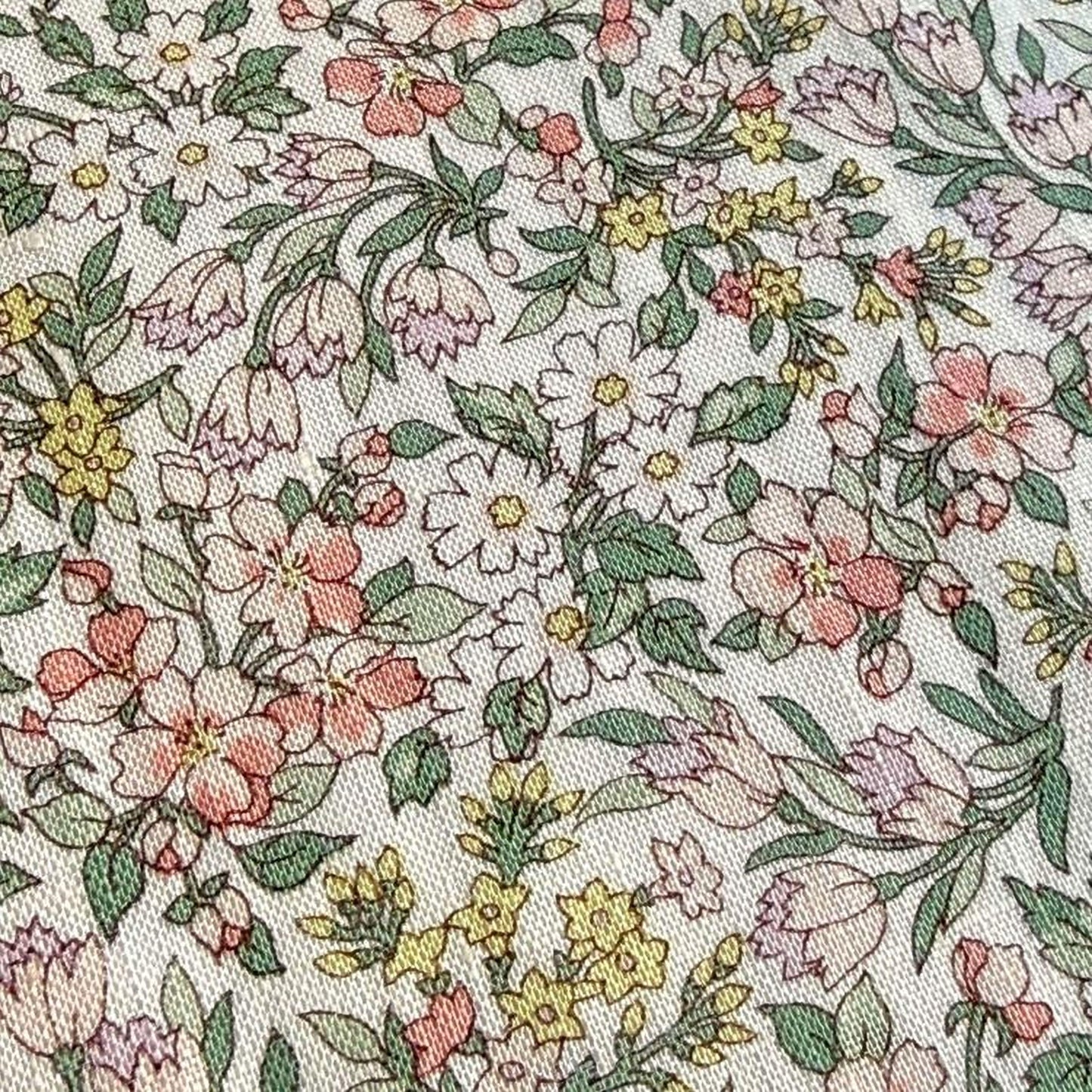 a close-up view of a fabric with a floral pattern. The pattern consists of various flowers and leaves in different colors, including pink, yellow, and green. The flowers are arranged in a way that creates a visually appealing and intricate design.