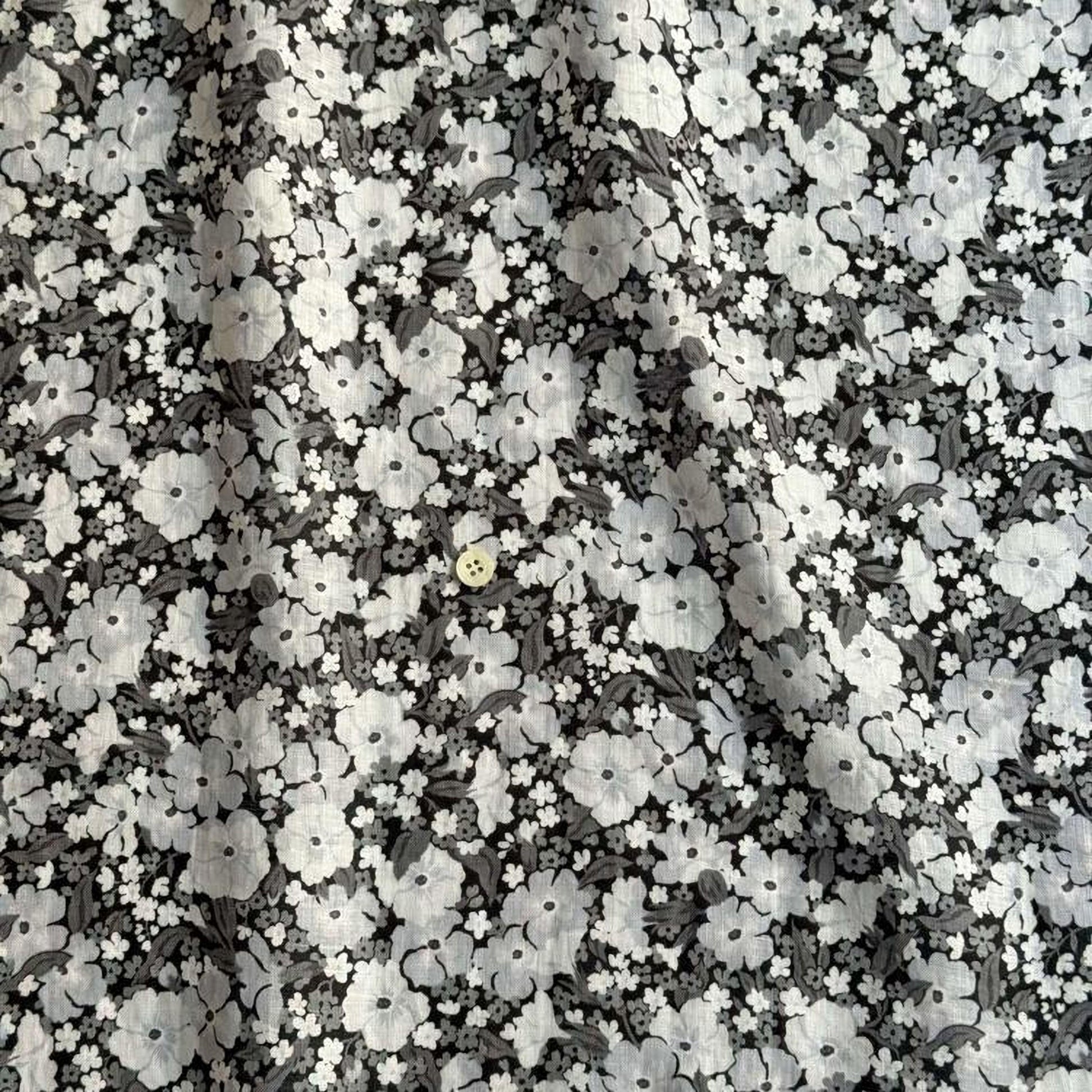 a close-up view of a fabric with a black and white floral pattern. The fabric appears to be made of a material with a floral design, and there is a small button visible in the center of the fabric.