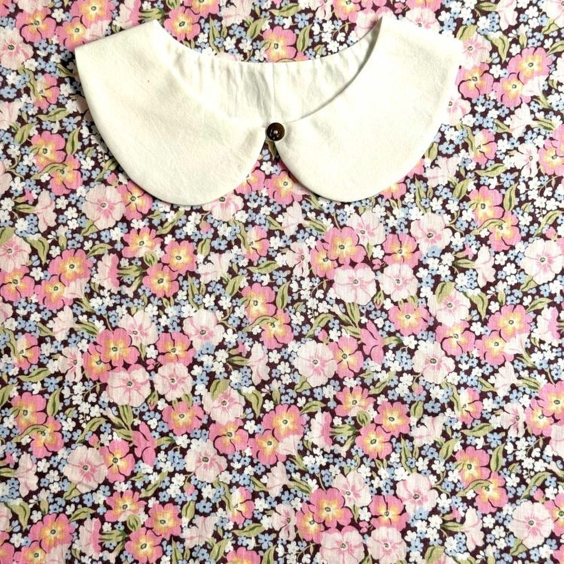 a white collar with a button, placed on a background with a floral print.