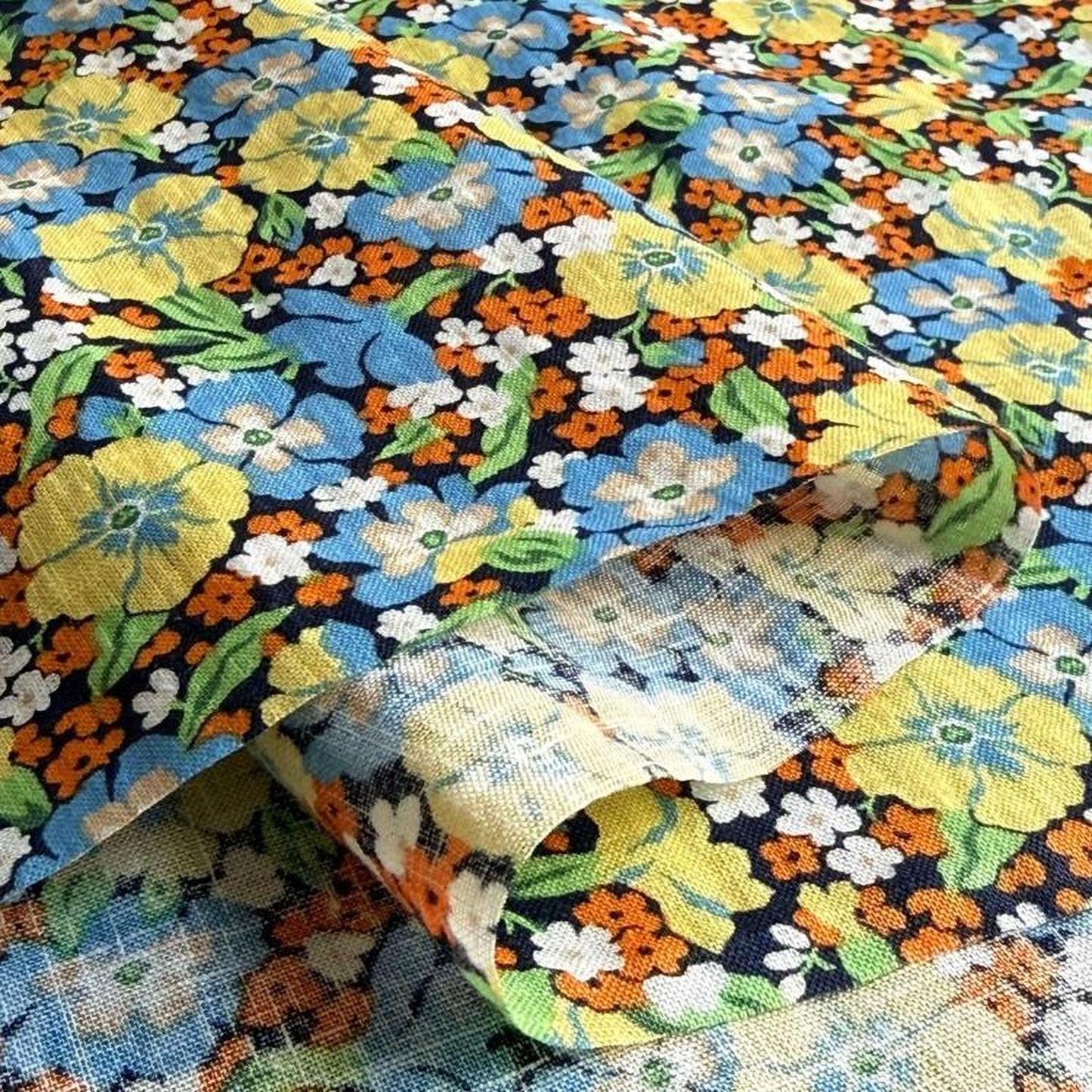 a close-up view of a fabric with a vibrant floral pattern in shades of yellow, orange, blue, and white. The fabric appears to be a piece of cloth or textile, with the intricate design and colors creating a visually striking and eye-catching pattern.